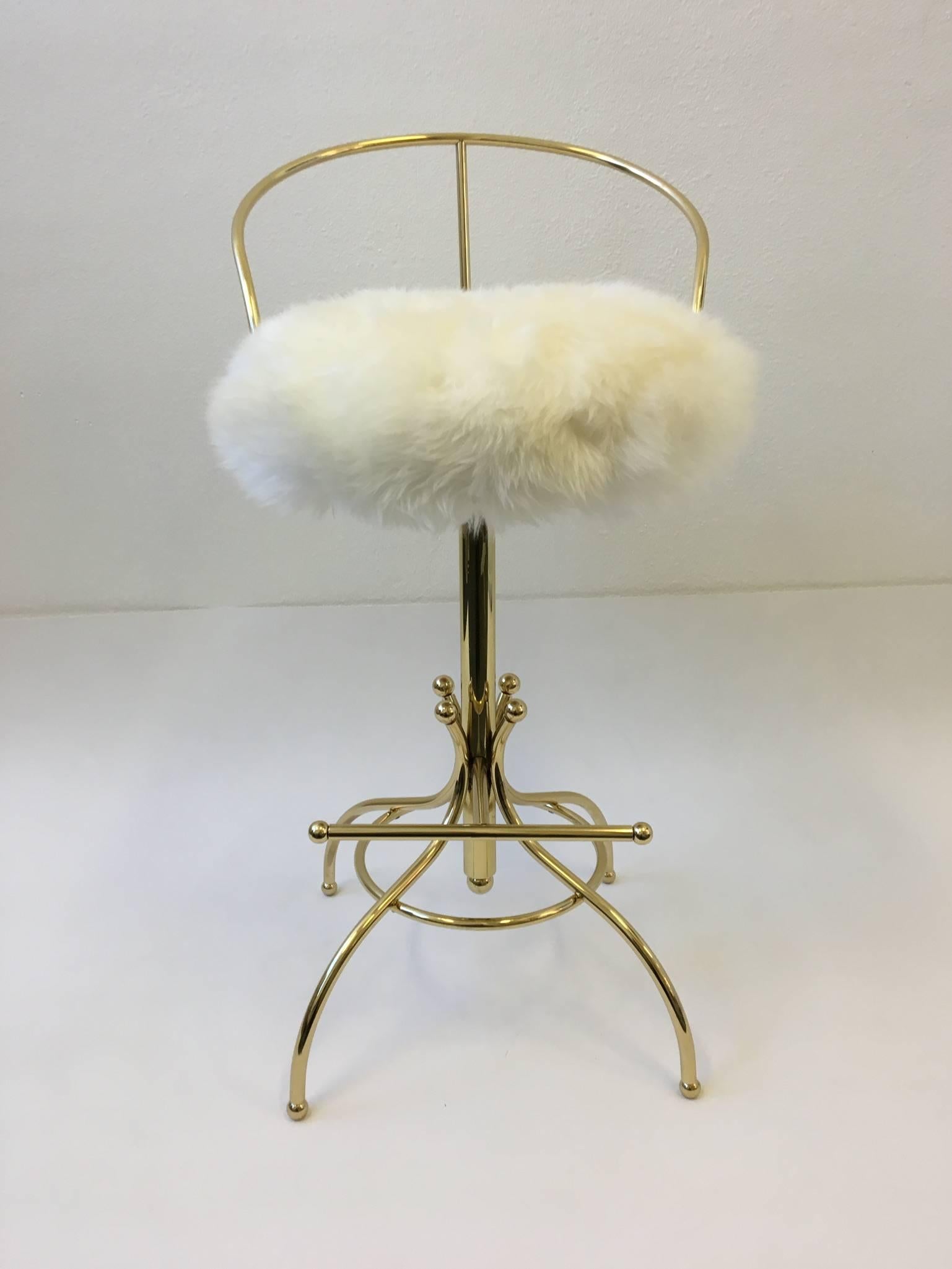 A glamorous polish brass swivel Sammy Davis bar stool, part of the Ball line designed by Charles Hollis Jones for Hudson Rissman in the 1960s. The stool swivels 360. Newly replated and reupholstered with sheepskin. 
Dimensions: 36.5