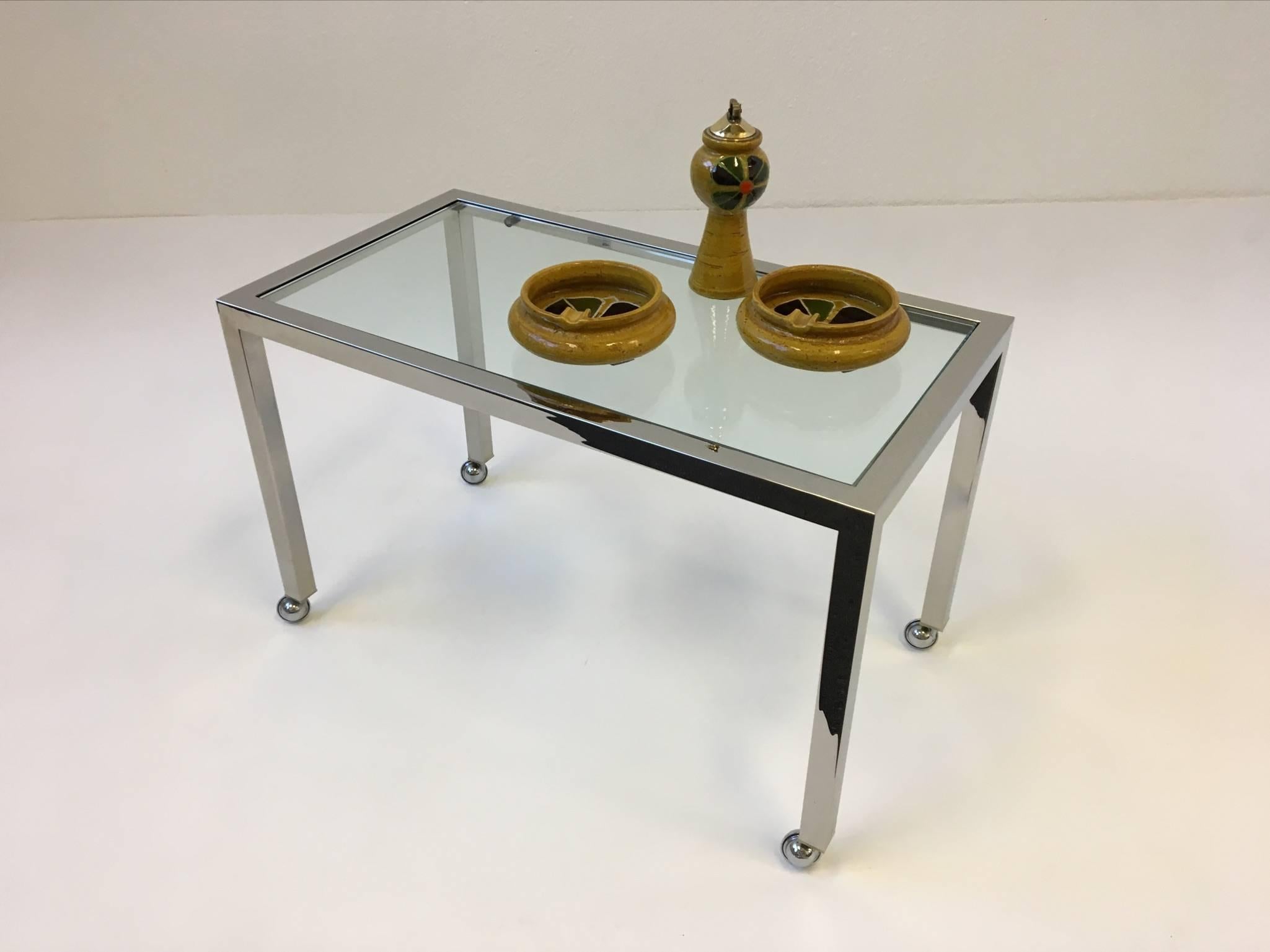 A simple but elegant chrome and glass side table made by Design Institute America in the style of Milo Baughman.
The table has small chrome caster. The glass insert is 1/2" thick. The table in original condition.
Dimensions: 26" wide,
