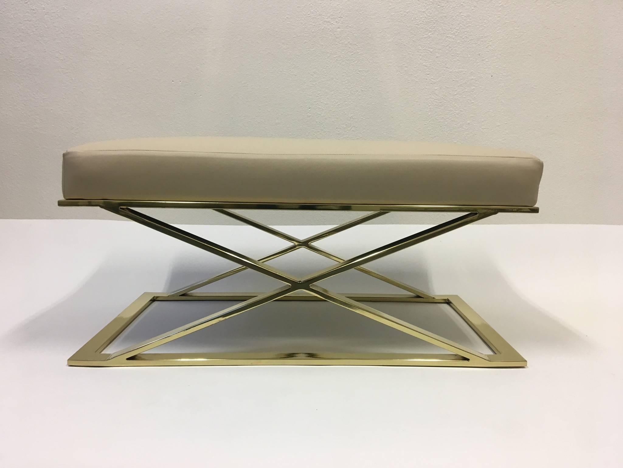 A glamorous pair of polished brass and cream leather X-base benches designed by Milo Baughman for Thayer Coggin in the 1970s. 
We purchased them in this condition (excellent). We believe they have been replated and reupholstered with this soft