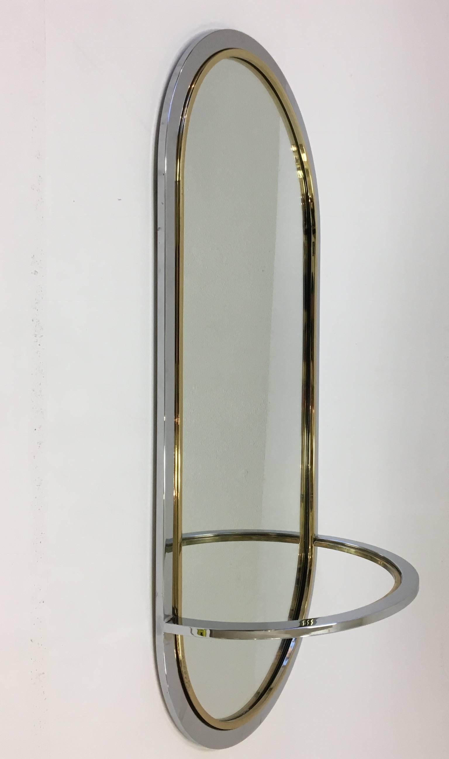 A glamorous chrome and brass race track wall mirror with a demilune shelf. Designed by Milo Baughman for Design Institute of America in the 1980s.
Dimensions: 24 inches high 20 inches wide 11 inches deep.