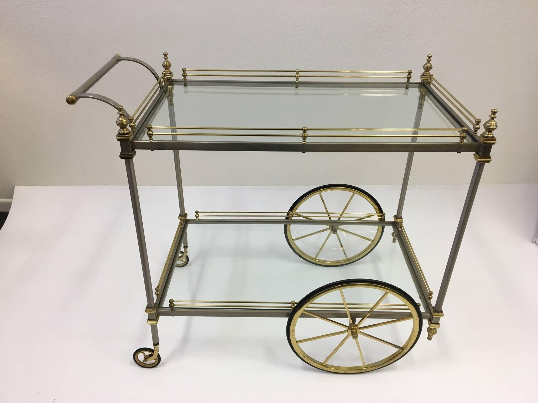 A glamorous 1960s Italian stainless steel and brass with glass inserts bar cart by Maison Jansen. New glass inserts. Still retains the metal made in Italy tag. 
Dimensions: 37.5 inches wide, 20.5 inches deep and 32.5 inches high.
 