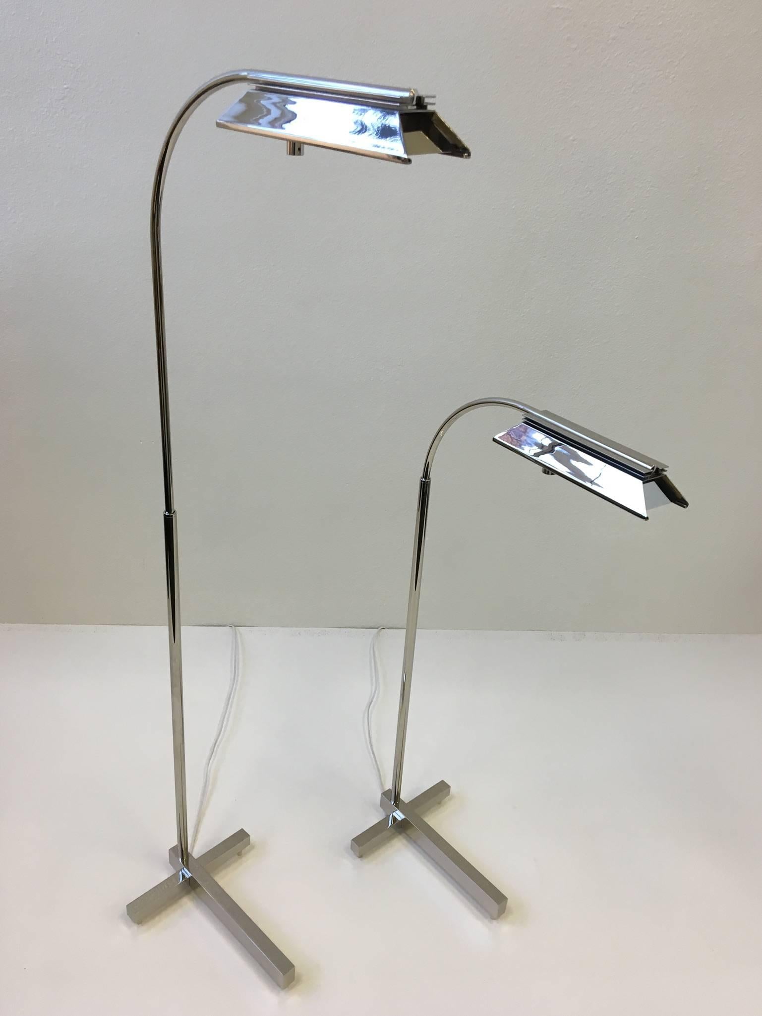 A beautiful pair of polished nickel adjustable floor lamps by Casella Lighting from the 1970s. The lamps have been newly rewired and replated. The lamps have a built in full range dimmer. They take a 100 W Halogen bulb. 
It has a 360 swivel and