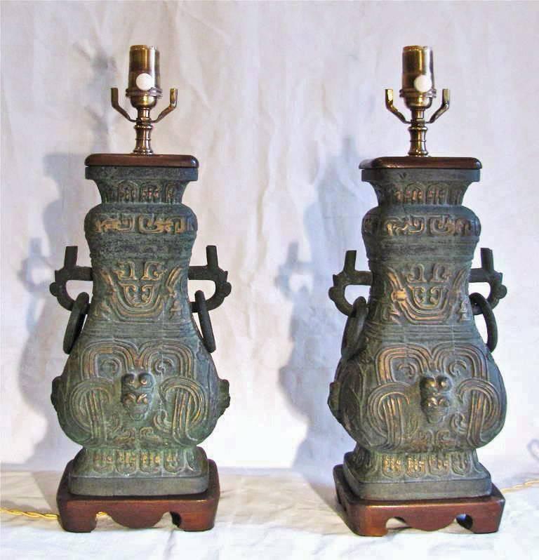 Single Asian motif aged bronze table lamps with wood fittings in the style of James Mont. Rewired with brass fittings in a bronze finish, full range dimmer socket and French style rayon covered cord. 
 