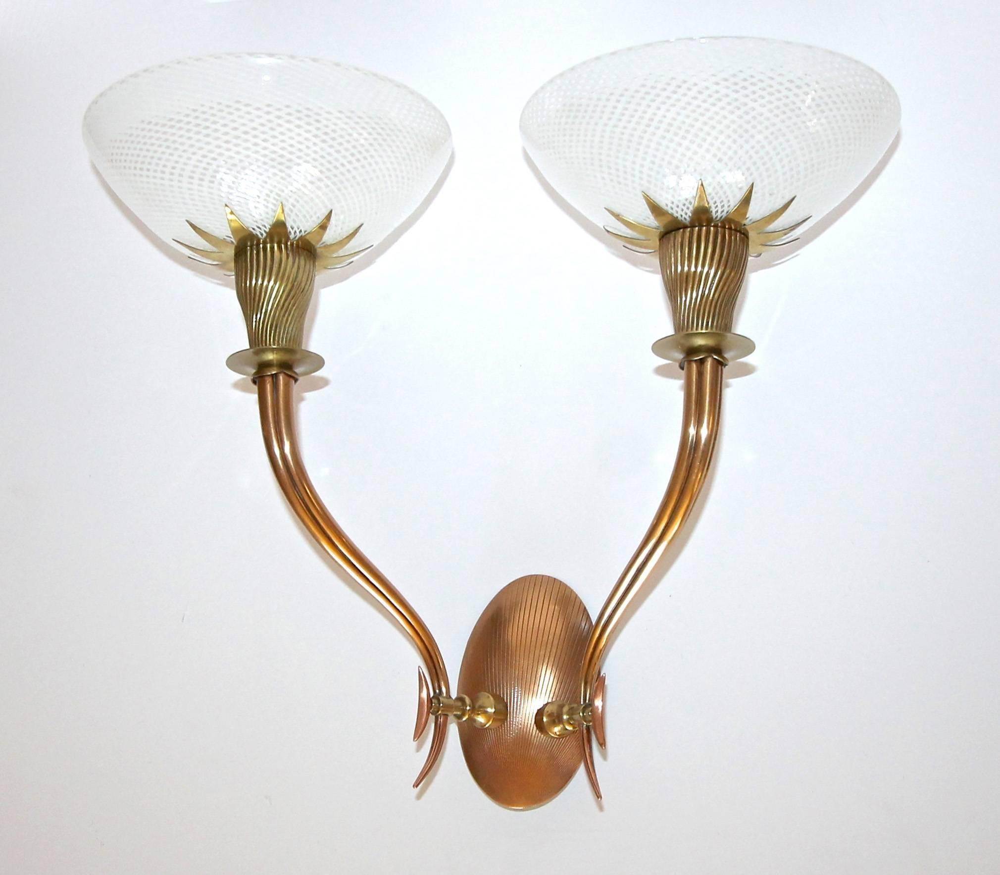 Exceptional pair of Italian Art Deco wall sconces alternating in brass and copper with beautifully scrolled arms and exquisite mezza filigrana white caned glass shades by Venini. Newly wired. Each sconce uses 2 - 40 watt max candelabra base bulbs.