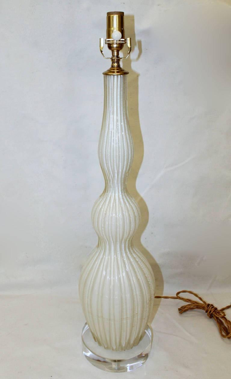 Beautiful Italian Murano cased glass lamp in white with subtle gold inclusions. A tall lamp in triple good form with thick vertical ribs of clear glass. Newly wired for US on custom acrylic base with brass fittings, full range dimmer socket and