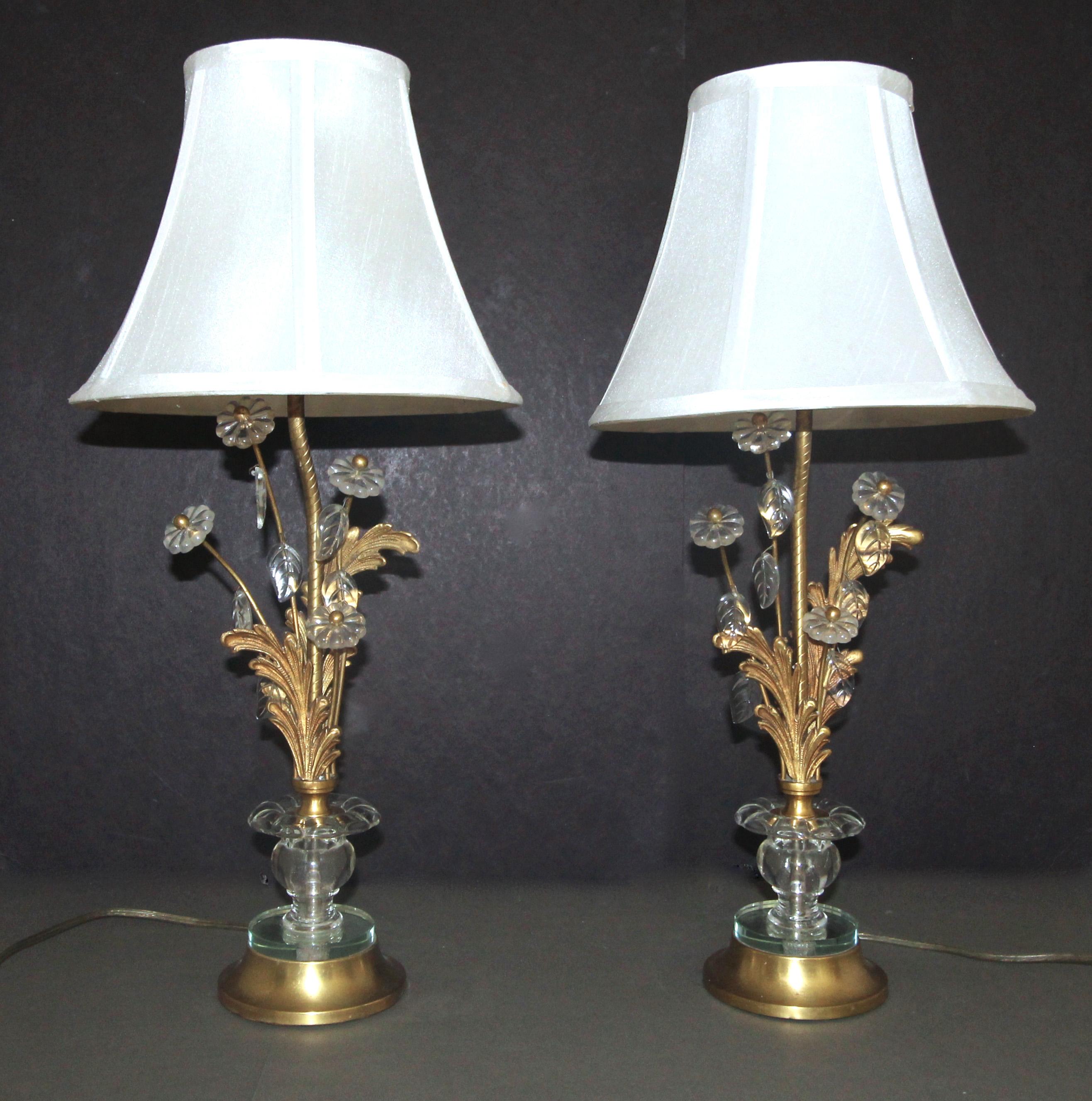 A pair of smaller scale French brass table or buffet lamps. Decorated with glass rosettes and leaves, and finely crafted foliate embellishments. Base is bass and mirrored glass. Each light uses regular A base bulb.
Shades included. 

Measures: