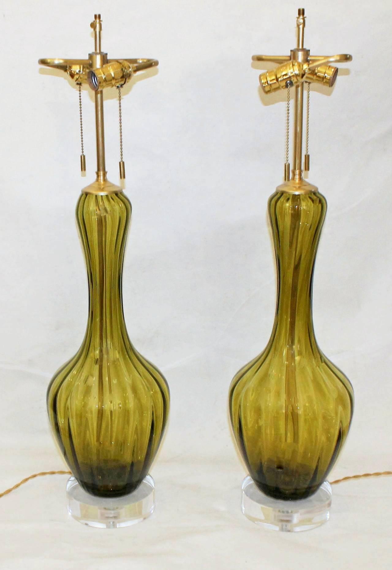 Pair of absinthe green colored Italian glass lamps on custom acrylic bases with new brass fittings. Newly wired for US with on/off double clusters, adjustable shade risers and French style rayon covered cords. Glass lamps in this more simple style