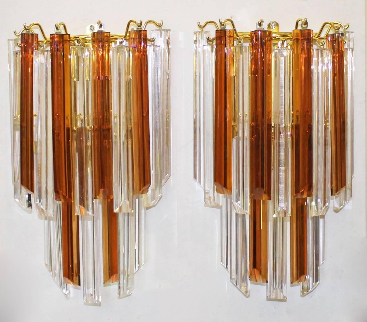 Pair of large Italian Venini style triedi prism wall sconces in burnt sienna and clear crystal glass with gold-plated back plates. Each sconce uses 3 - 40 watt candelabra base bulbs. Newly wired for US.

Measures: 17