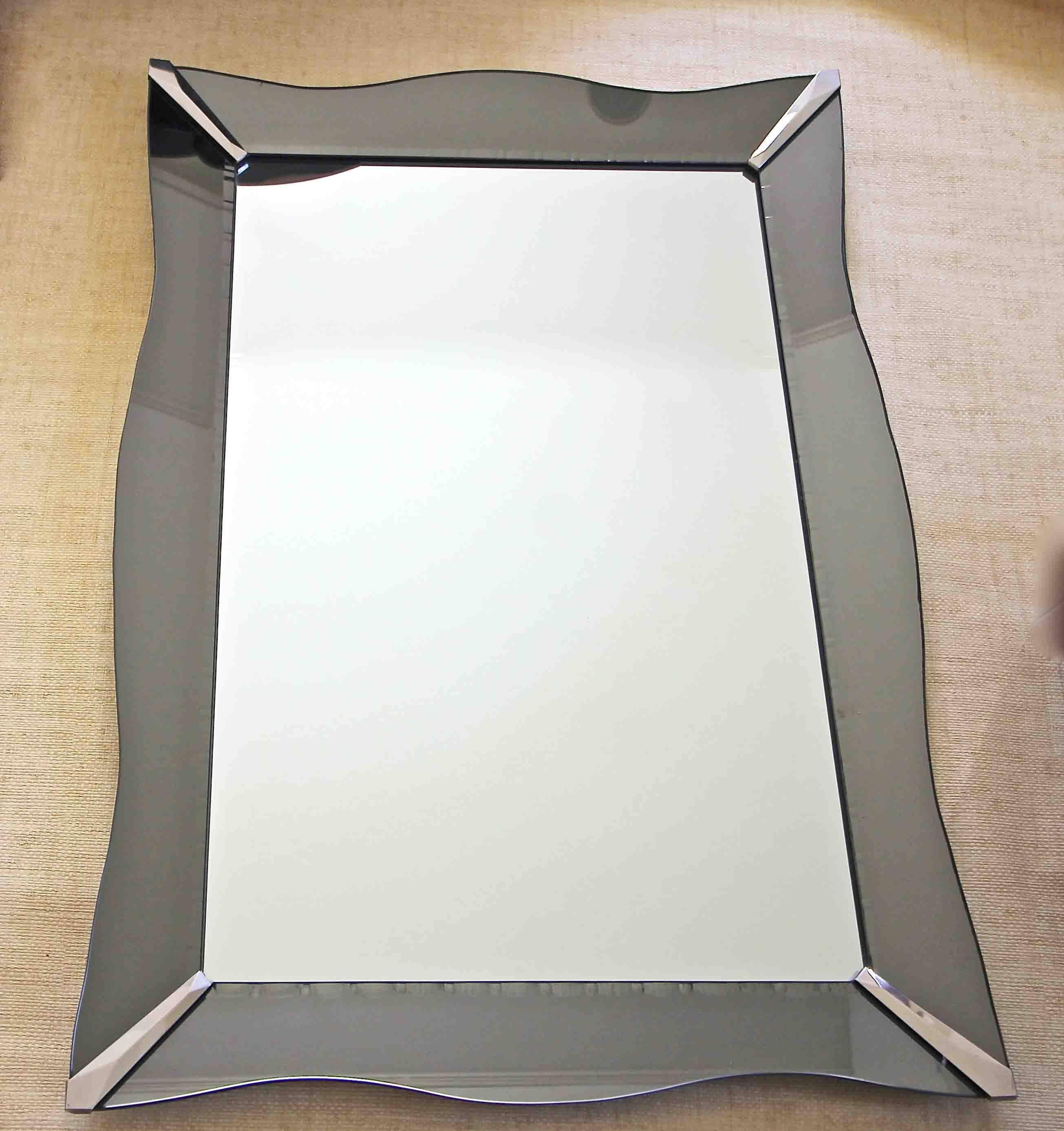 Rectangular shape Art Deco style wall mirror with smoke colored wavy curved glass panels on wood frame backing. Detailed wheel cut etched edges to interior side of smoke color glass panels. Can be hung vertically as shown or horizontally with added