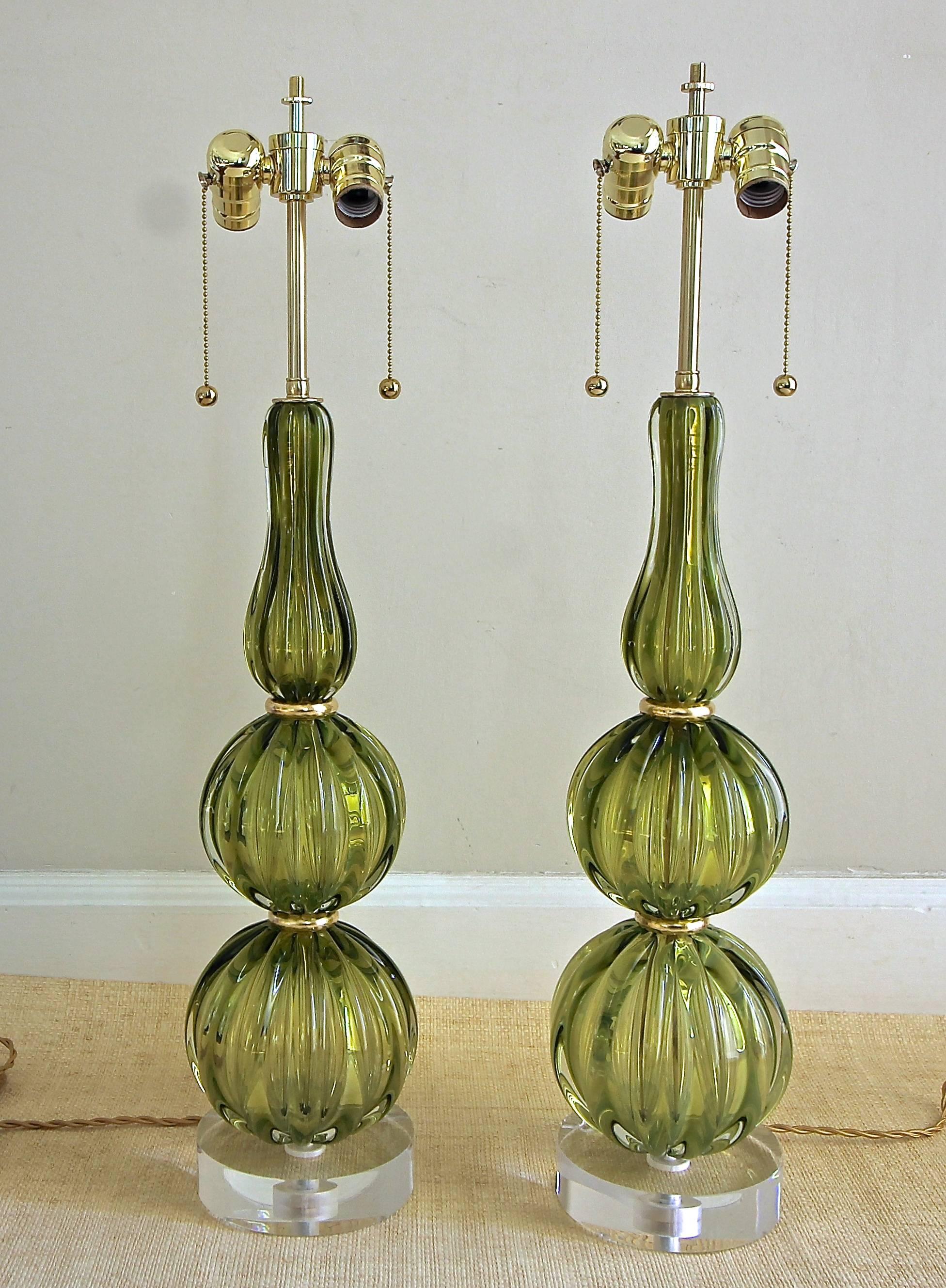 Pair of fabulous Murano thick handblown absinthe (green) colored ribbed table lamps by Seguso. Mounted on new custom acrylic bases with double cluster solid brass fittings, giltwood spacers and French-style rayon covered cords. Newly wired for US.