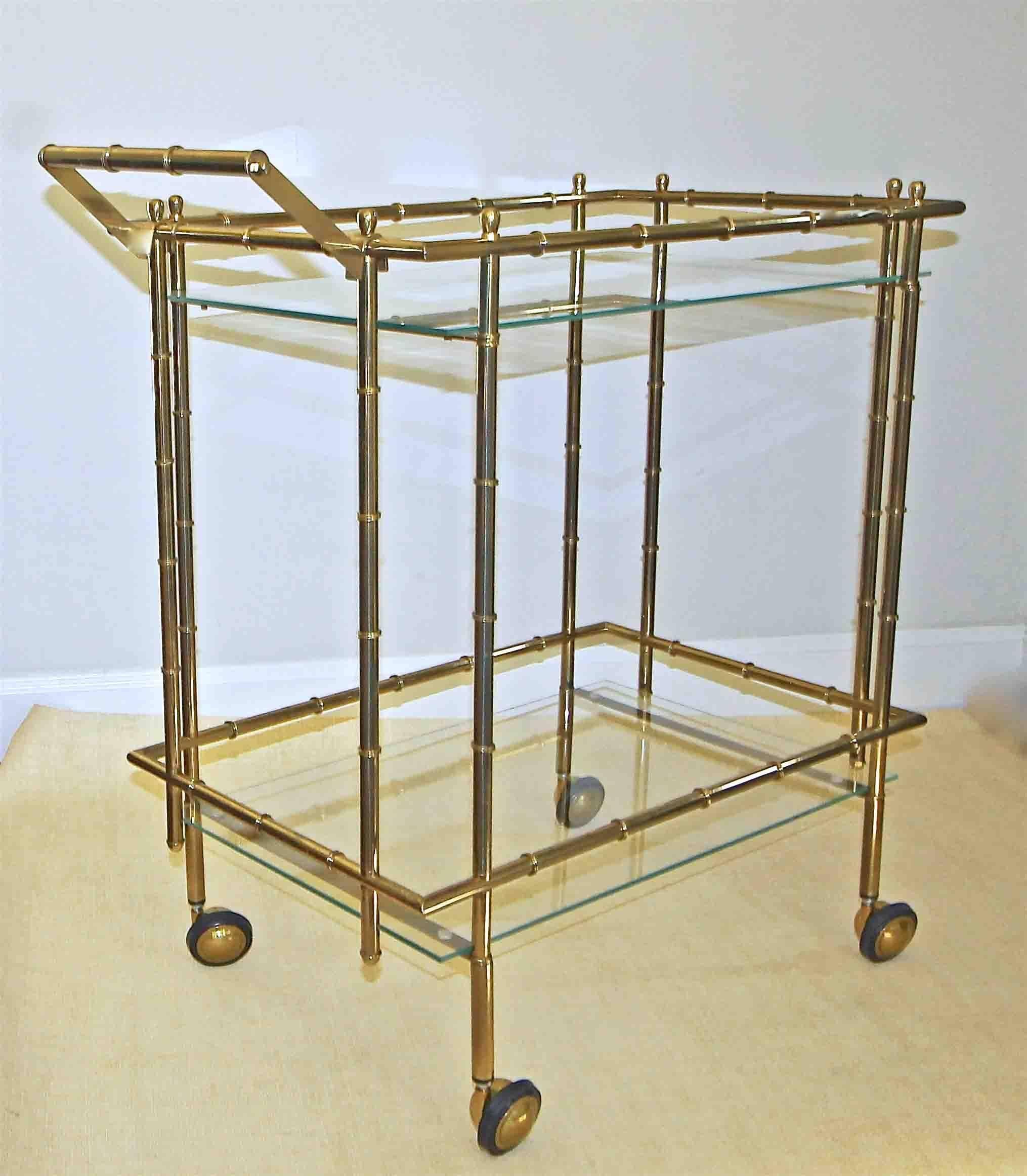 Nice scale two-tier faux brass bamboo bar cart, with glass inset shelves resting on caster wheels.

This item is located at our Dallas showroom.