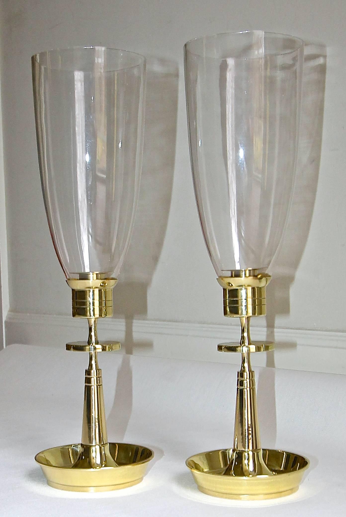 Pair of tall brass hurricane glass globes candlesticks by Tommi Parzinger for Dorlyn Silversmiths. Professionally polished and lacquered. Height of candlesticks without glass globes 9" tall, overall height with glass globe 19".