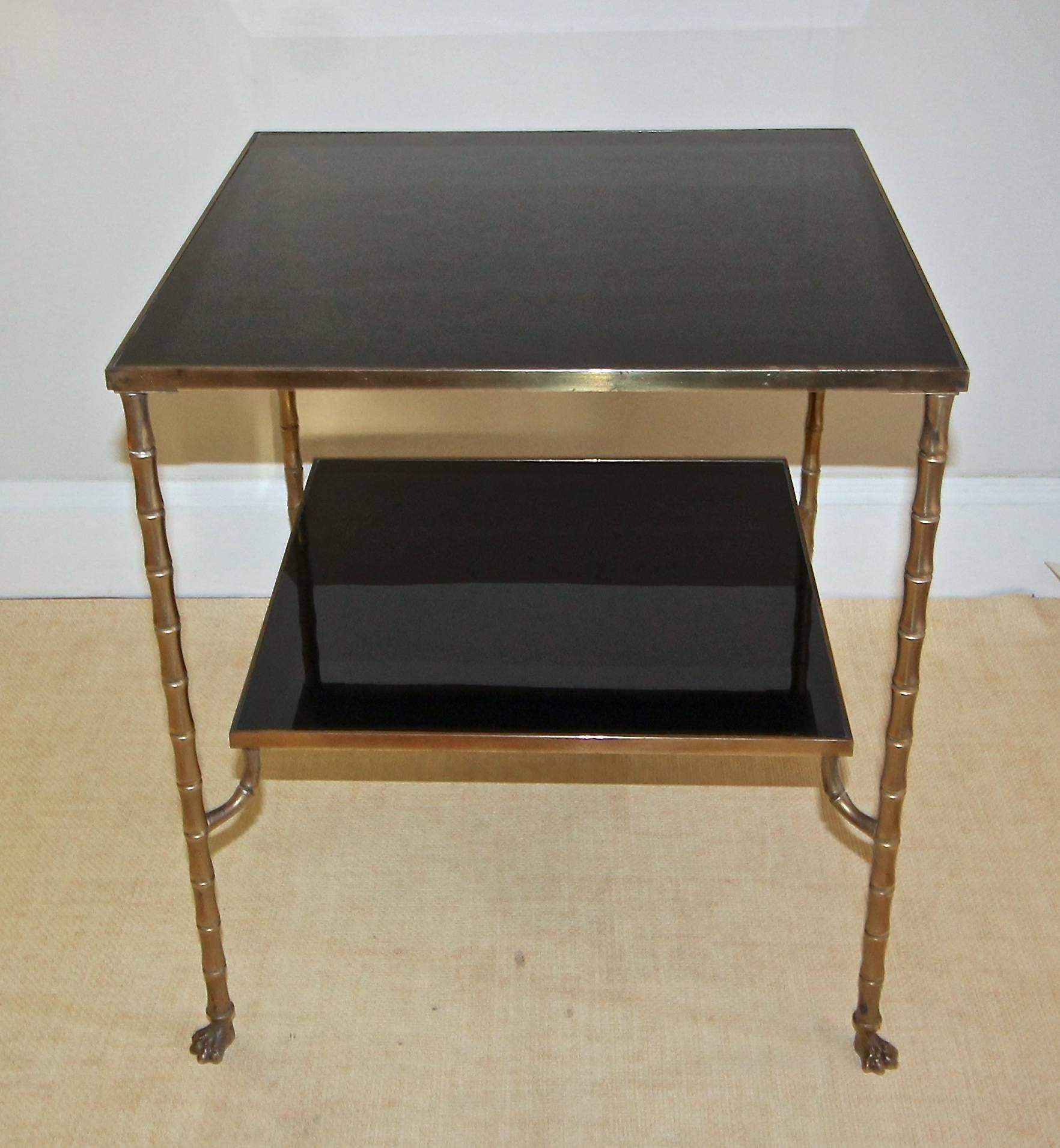 Single French Maison Baguès bronze two-tier side or end table with detailed paw feet. Warm patina with superb crafted detailing. Original black glass inset tops.
