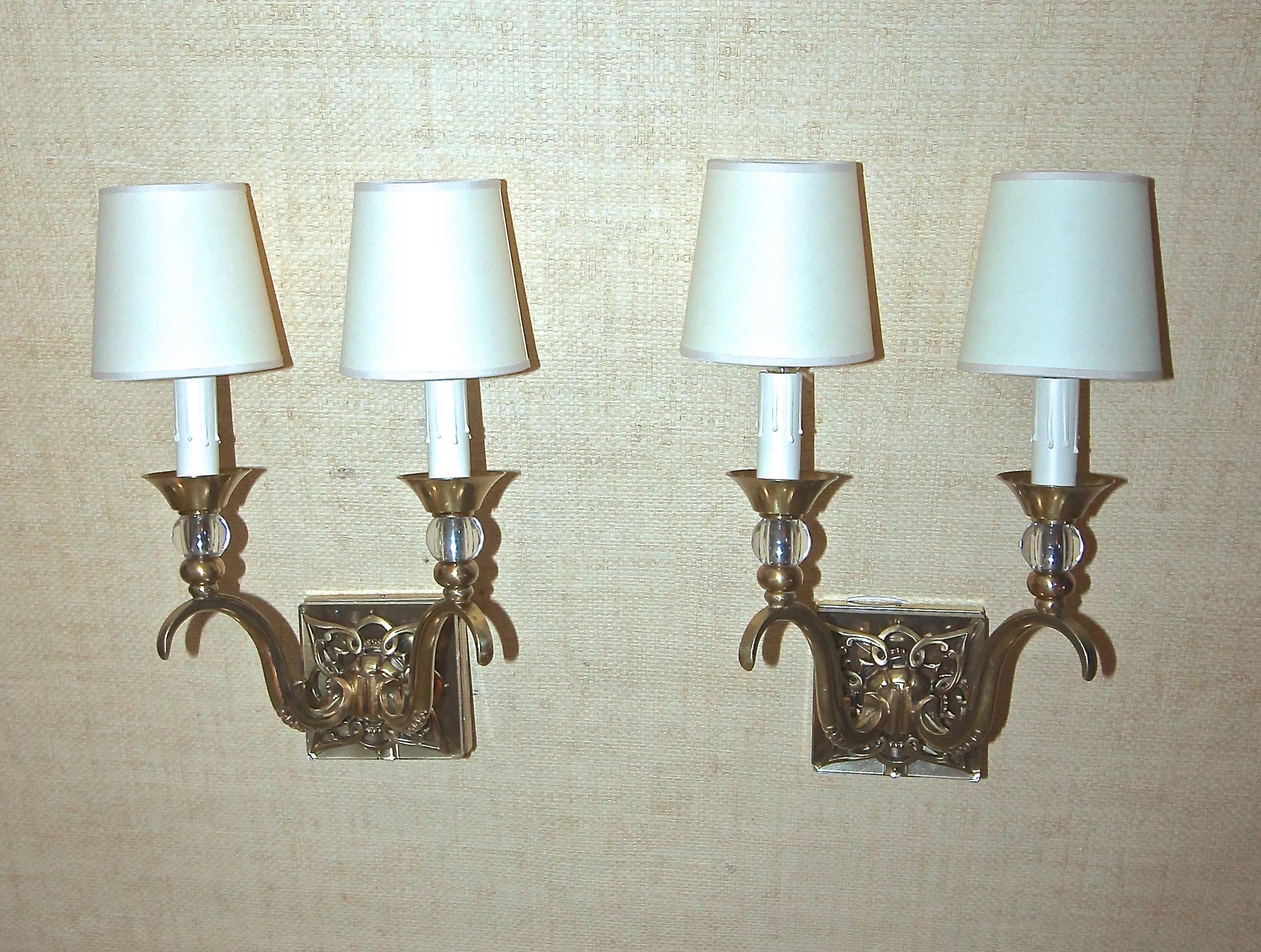 Pair of elegant French two-arm bronze or brass and crystal wall sconces attributed to Jules Leleu. Each sconce uses 2 - 40 watt max candelabra base bulbs, newly wired. Paper shades are included. Overall height with shades 14", without shades