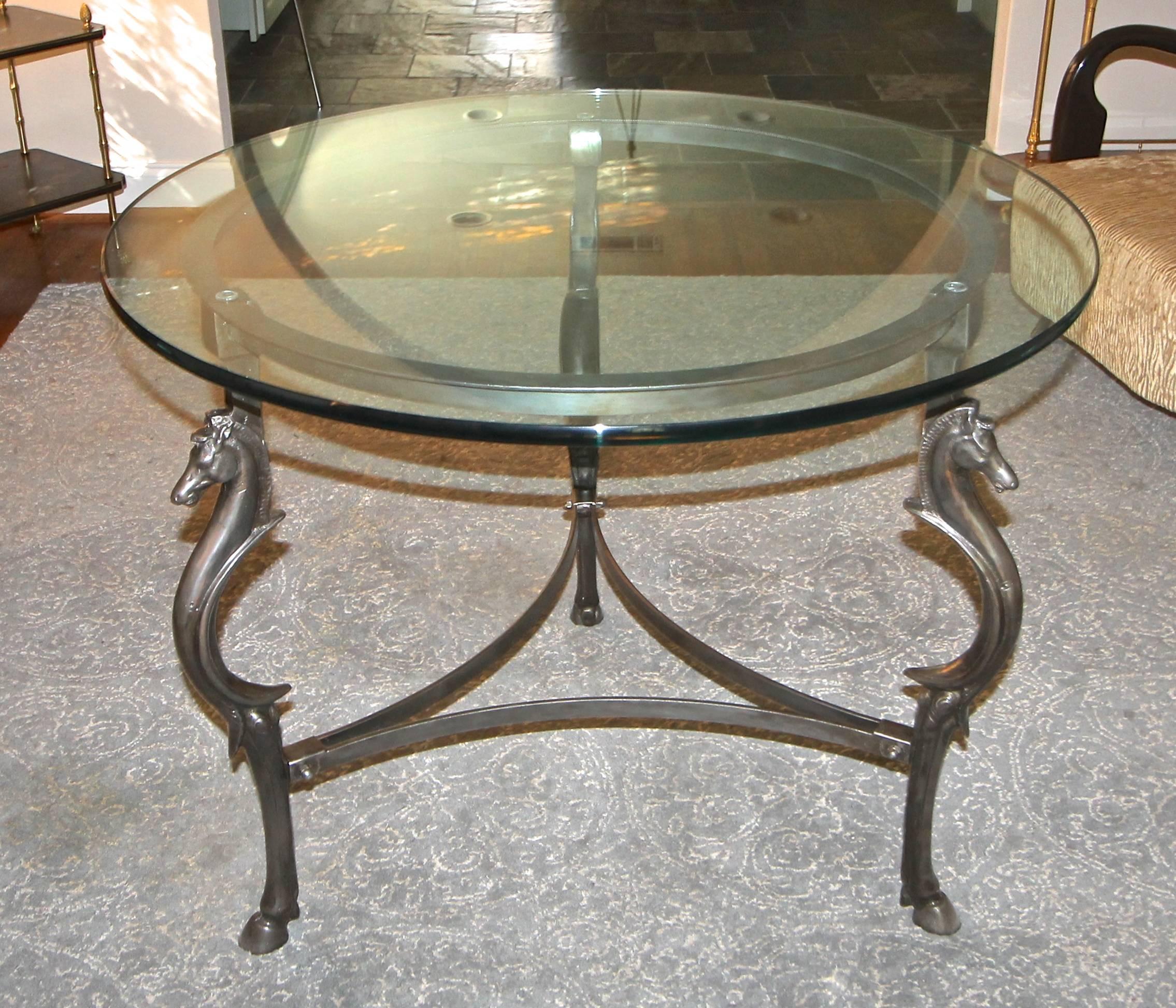 Center table with decorative cast steel horse (equestrian) motif legs. Thick round glass top rests atop. Possibly French in style of Maison Jansen or Moreux.