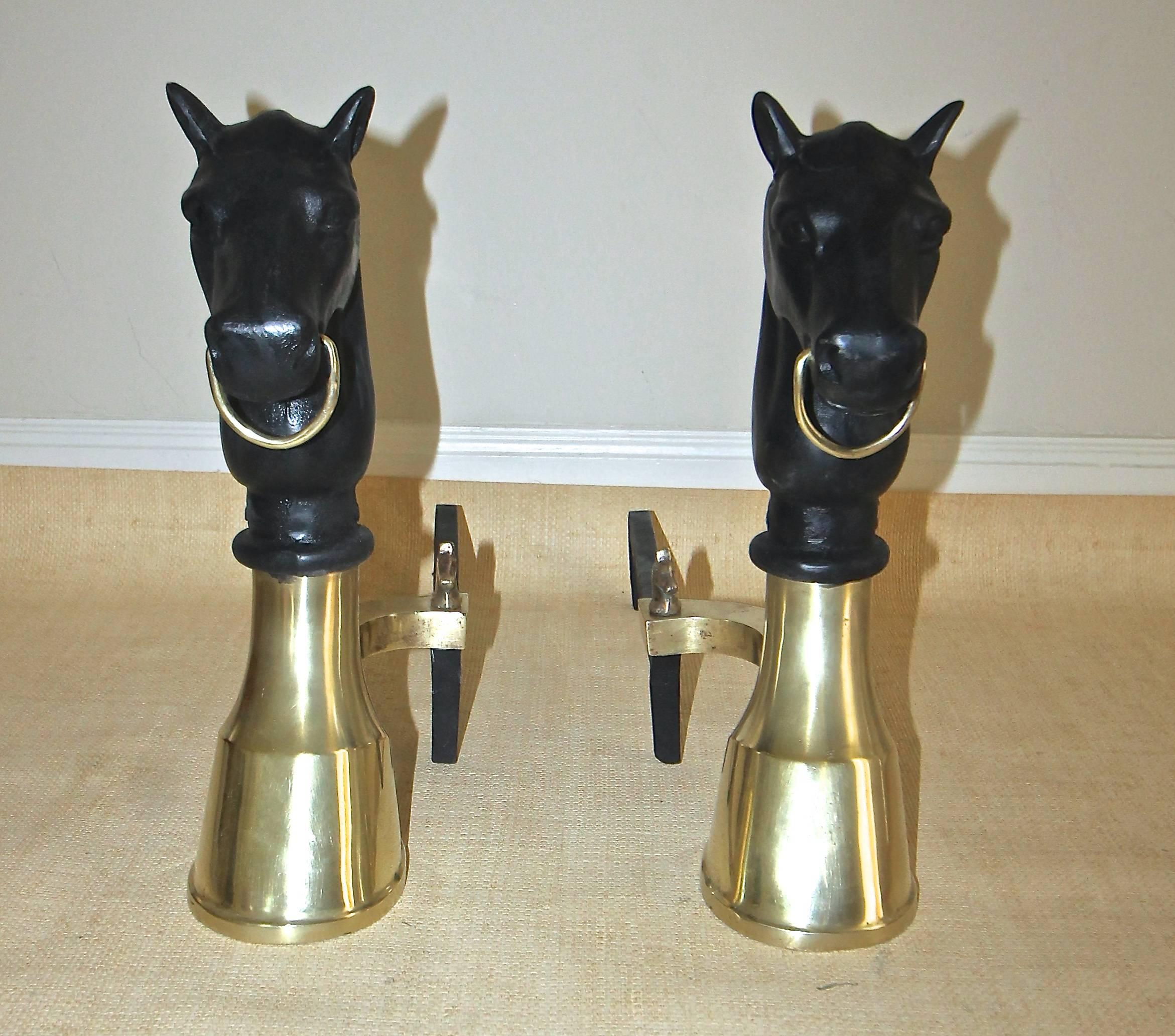 A very handsome pair of bronze or brass and cast iron andirons with a horse head and hoof motif and horse head finials at the base.