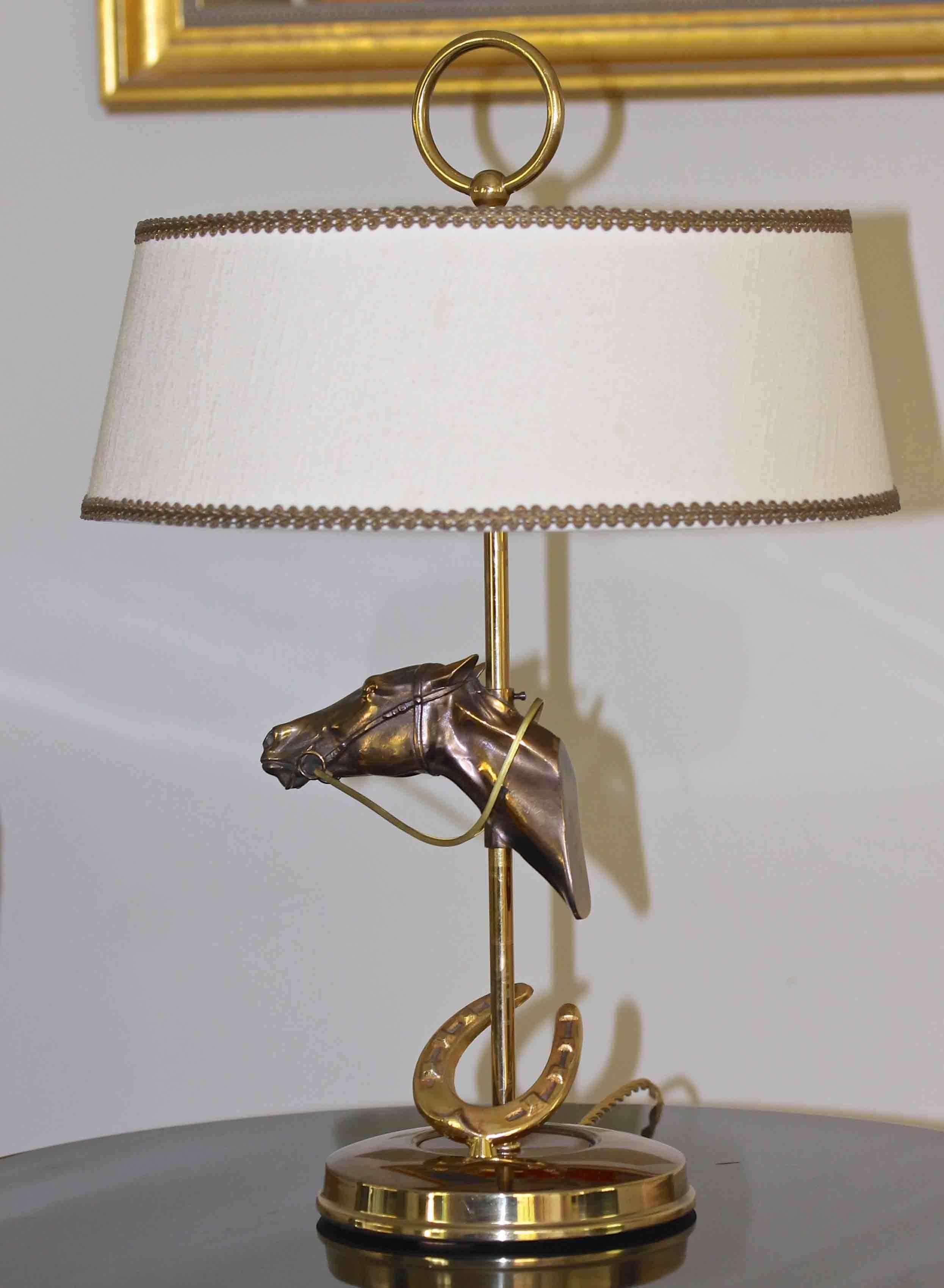 Unique smaller scale equestrian horse head and horse shoe motif brass finish table lamp from France. Original shade included. Uses two 40-watt round candelabra base bulbs. Newly wired for US with French style rayon covered cord. 

Size without