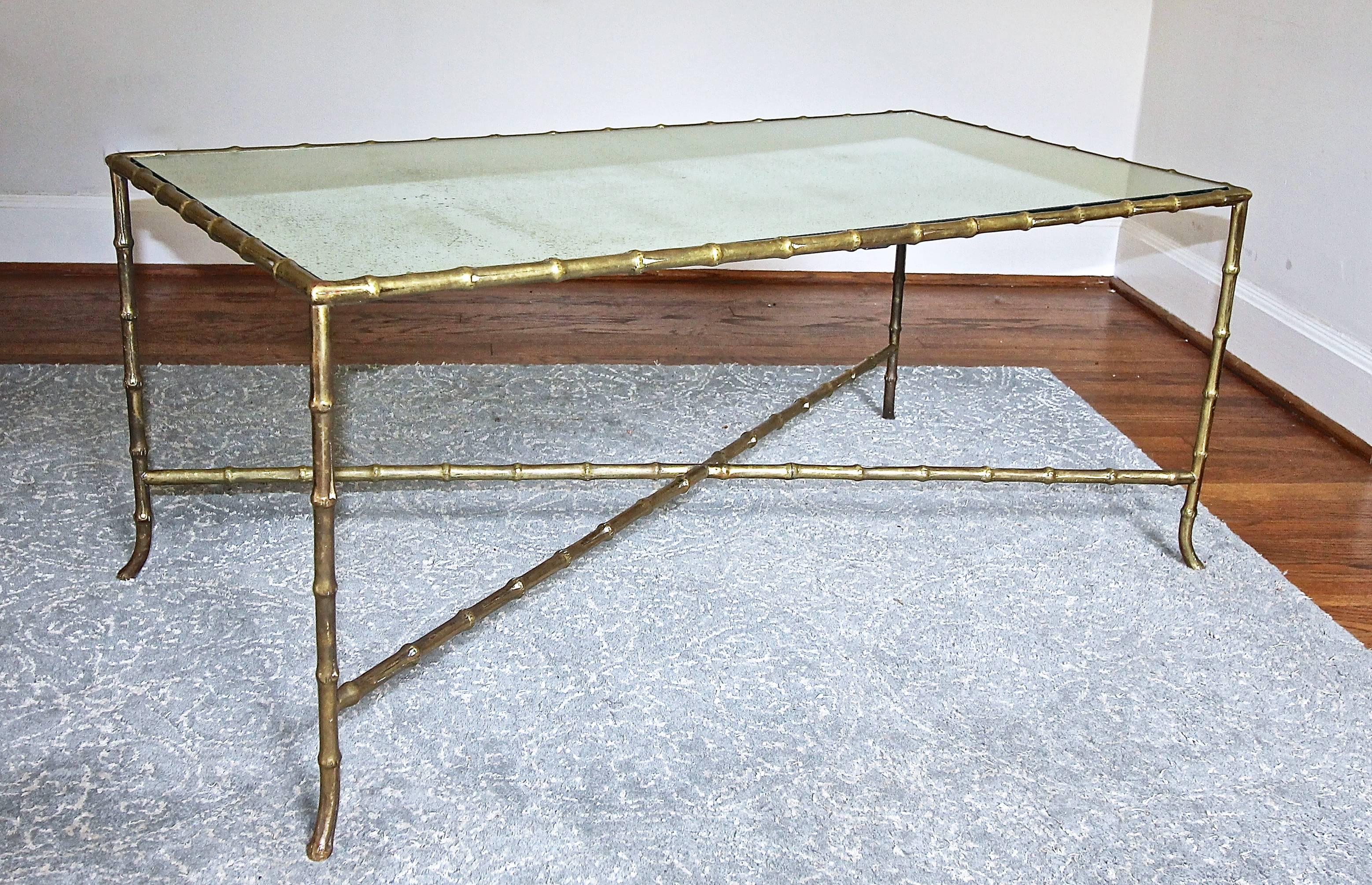 French faux bamboo bronze cocktail or coffee table with an "X" stretcher and inset antiqued mirrored top, in the style of Bagues. Beautiful warm patina to bronze. A high quality piece in a larger scale.

Measures: 41" L X
