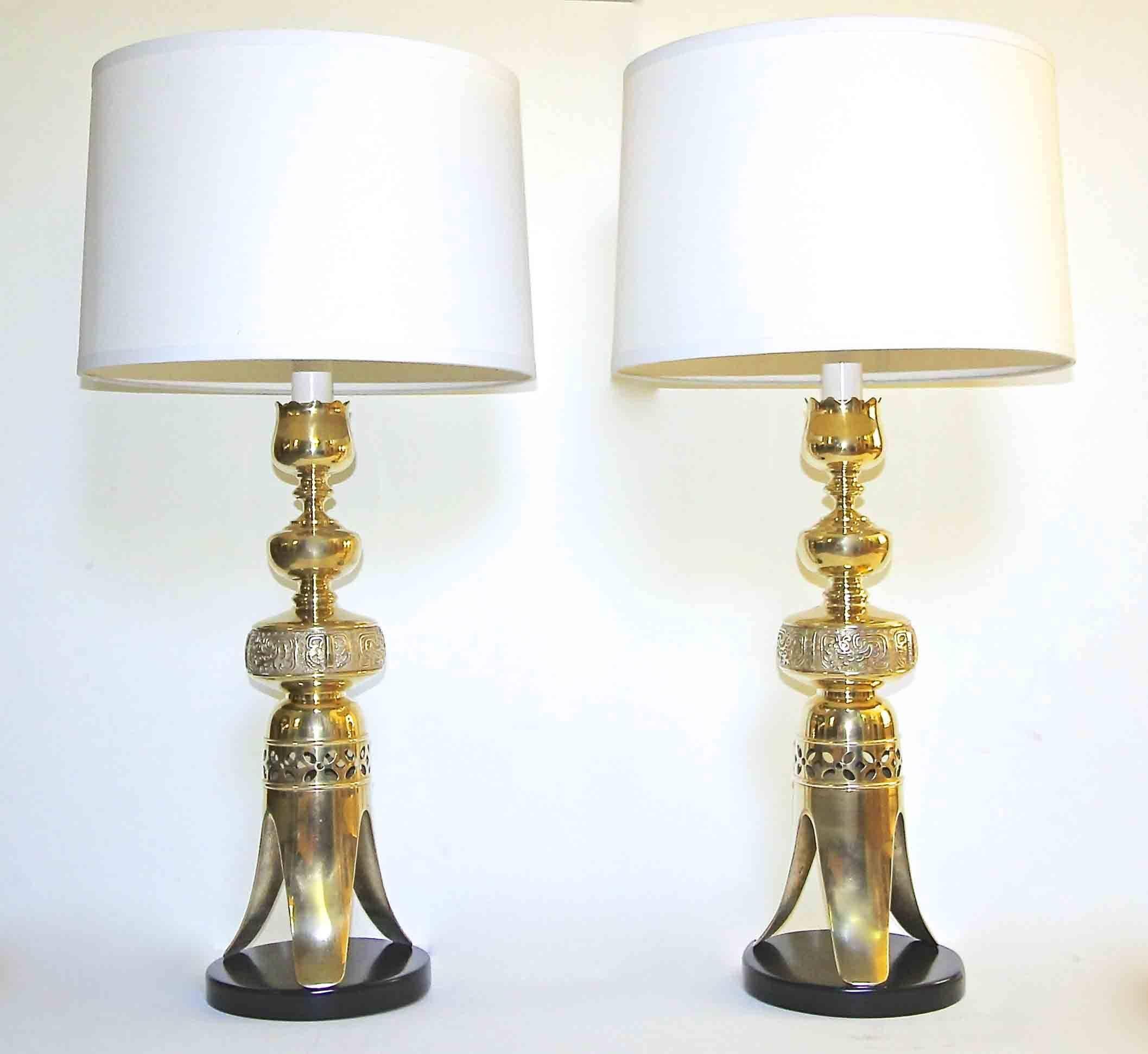 Pair of tall Japanese solid brass altar candlesticks converted to table lamps resting on black painted wood bases in the manner of James Mont. Newly wired for US with solid brass fittings, double on/off pull sockets and French style rayon covered