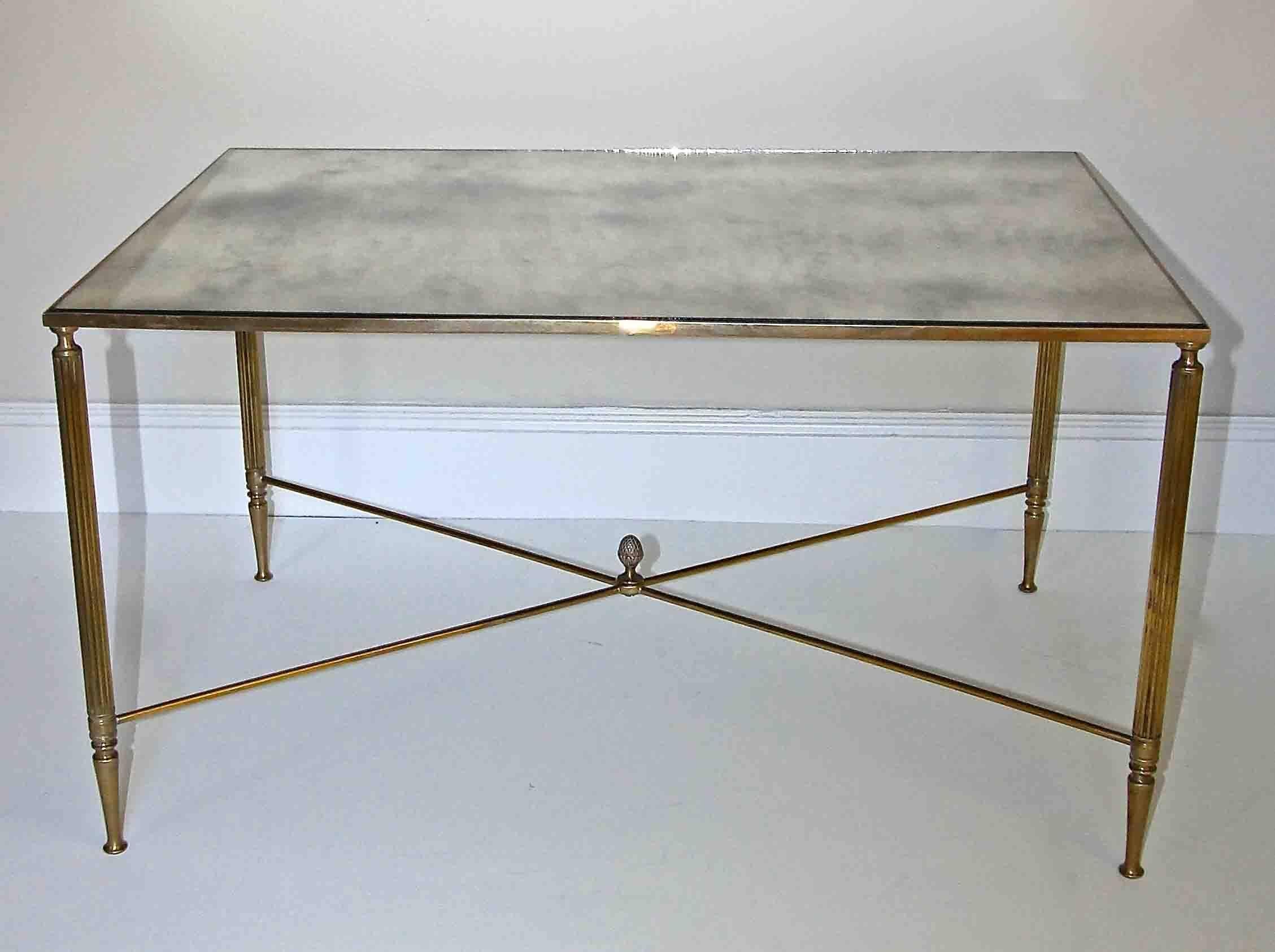French brass X base coffee or cocktail table with inset antiqued mirror top. Nicely detailed with reeded legs, X stretcher and acorn center finial.