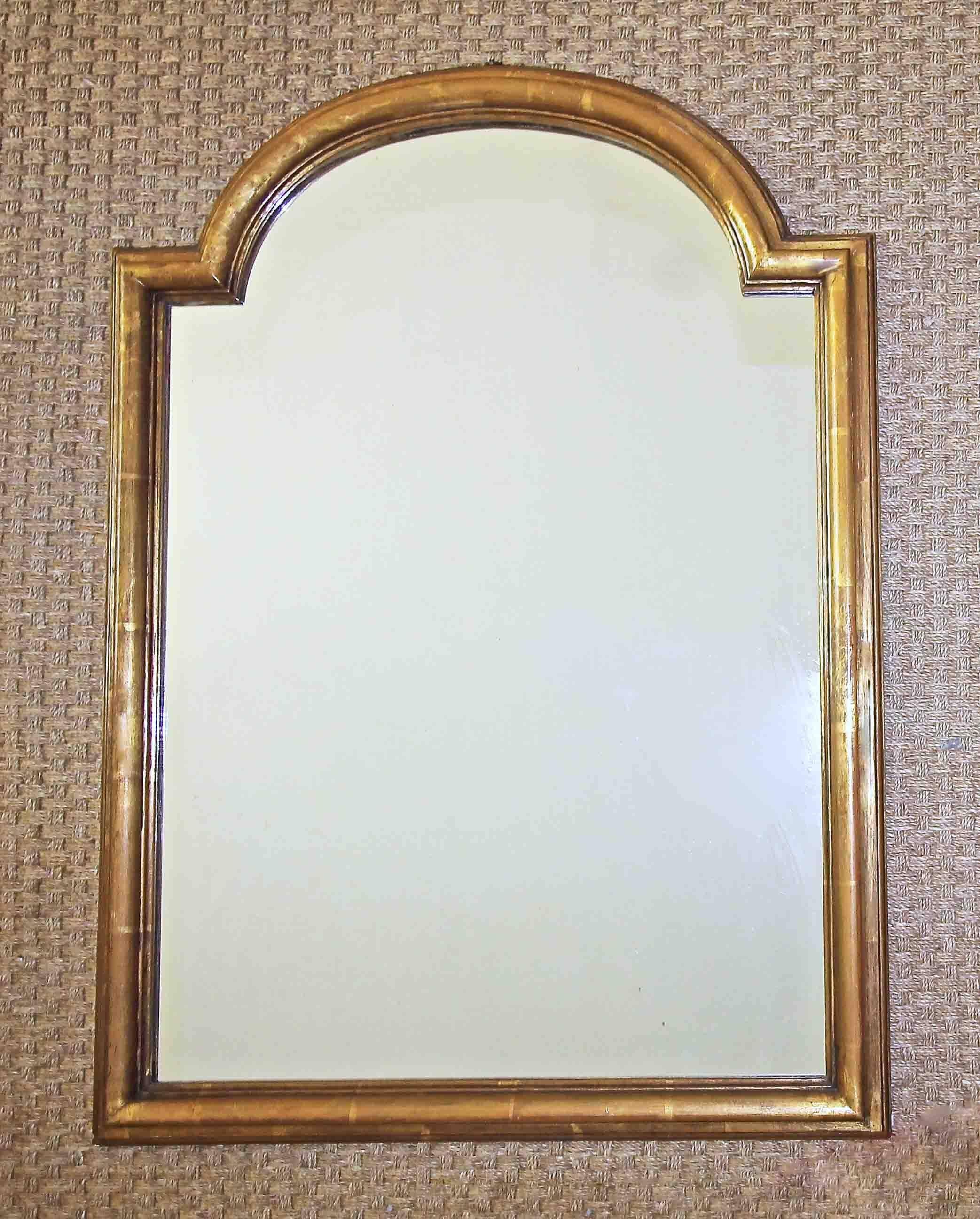 French arched top wood framed mirror in a worn gilt finish. A handsome and clean lined carved profile in the Louis Philippe taste that can be as easily placed in a traditional setting as a more contemporary one.

31.5