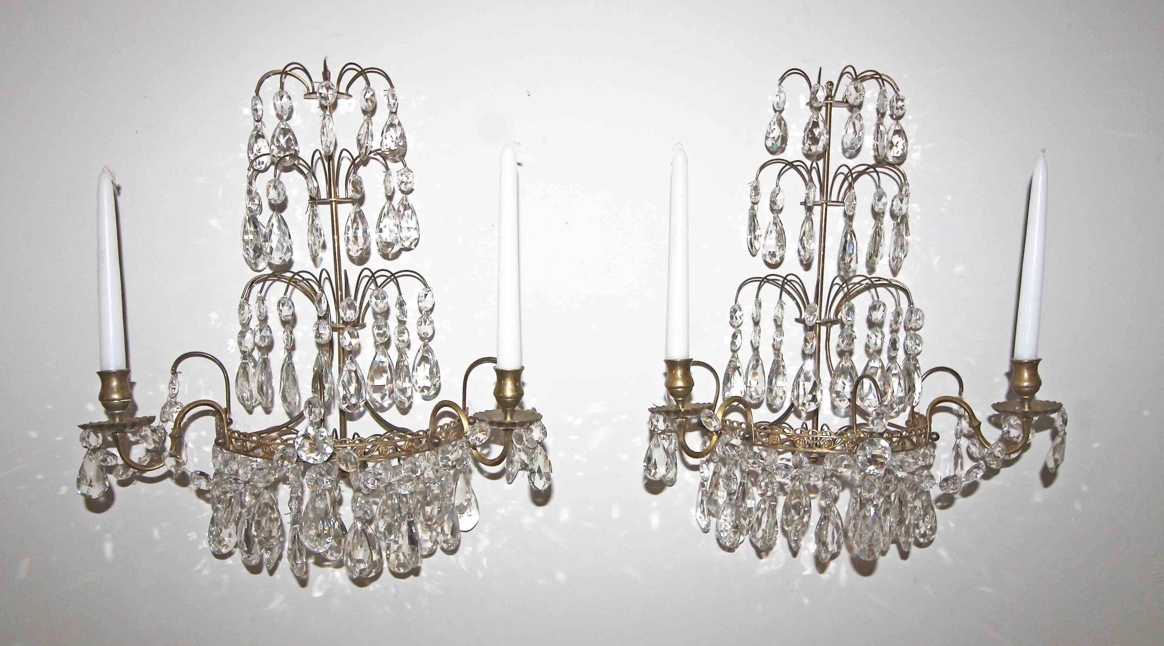 Pair of exquisite crystal and brass Swedish two-arm candle wall sconces. Nice detailing to the metal work with graceful crystal draping in the manner of the Gustavian period. Can be wired for an additional fee.