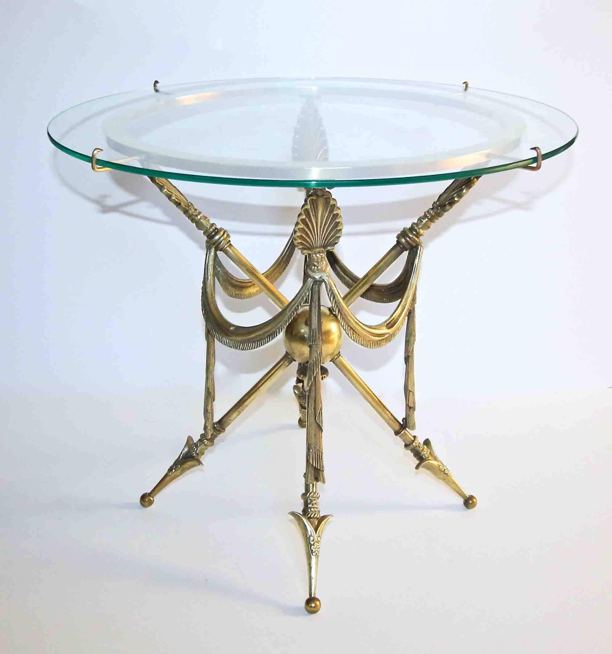 A brass side or occasional table with arrow and draped swag motif in the French Empire or Directoire style. New glass top is held to the circular brass top of table with attached arms.