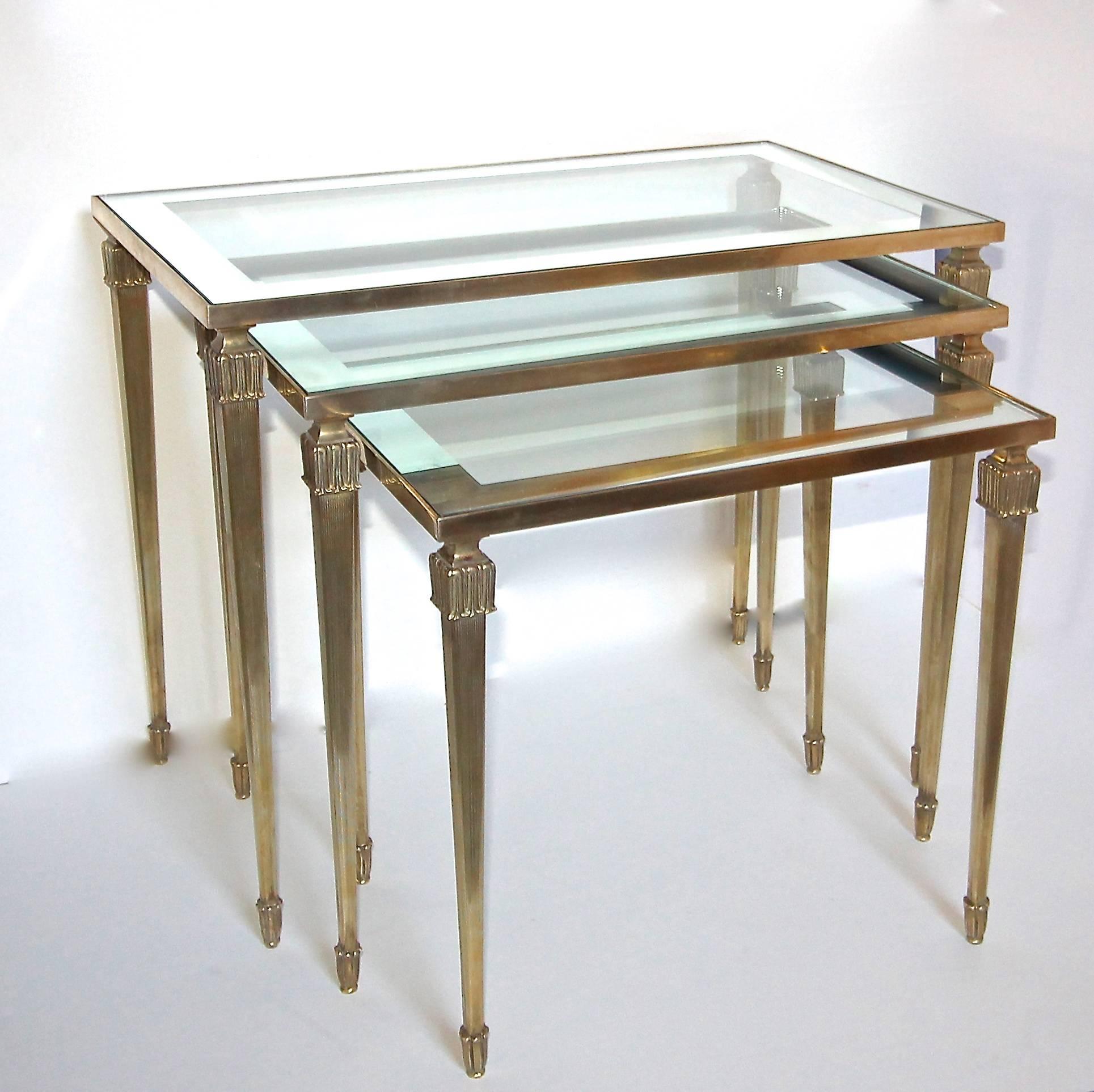 Trio of French solid brass nesting tables with mirrored edge glass tops, attributed to Maison Jansen. 

Size of each table: 
19" H X 23.5 W X 13.88" D.
17.25" H X 20" W X 12.75" D. 
15.5" H X 16.5" W X