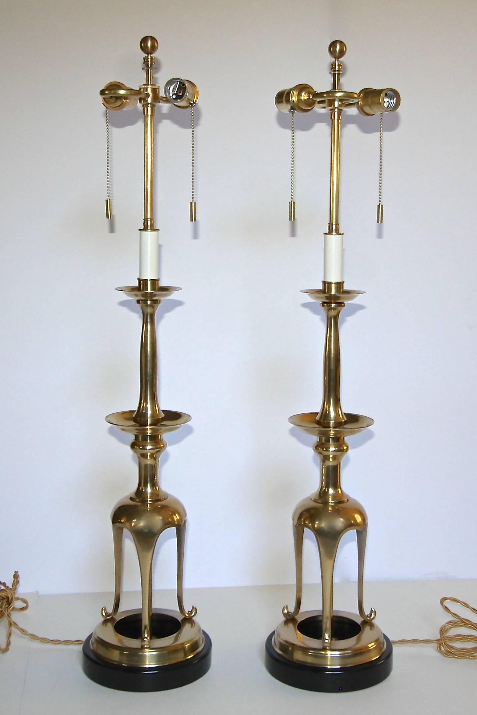 Pair of solid brass Asian Style candlesticks converted to table lamps resting on black painted wood bases. Newly wired for US with French style rayon covered cords and brass double cluster sockets. Shades not included for photography only.