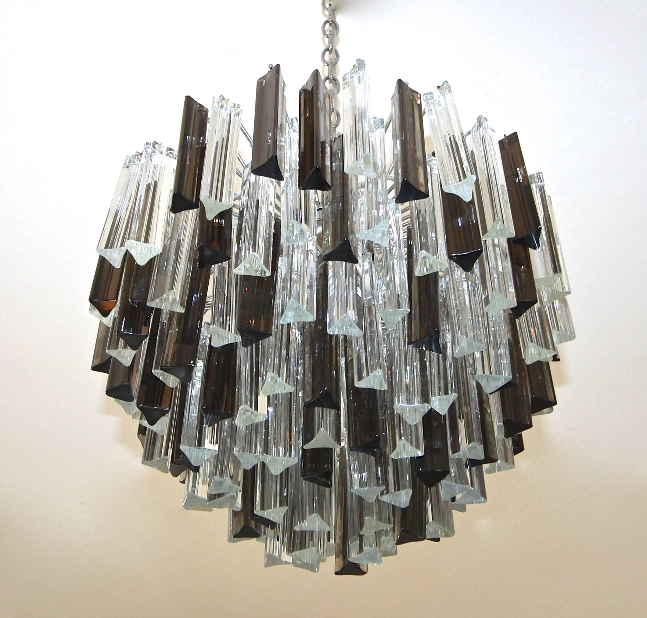 Round larger size multi-tier triedri glass chandelier with clear and smoke colored glass crystal prisms. Newly chrome-plated heavily constructed steel frame. Great vintage Italian Murano design in the manner of Venini and manufactured by Camer