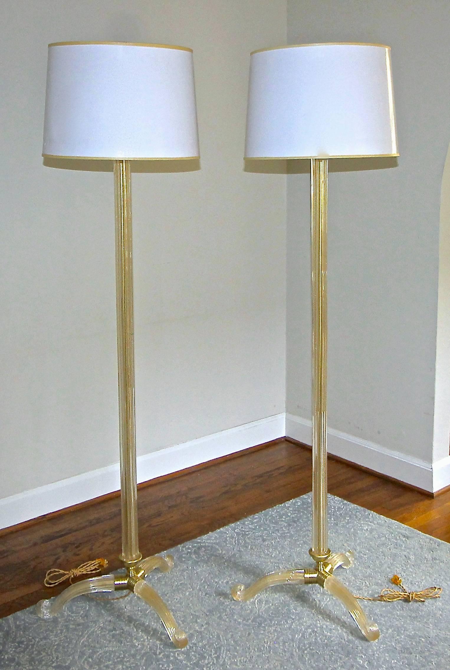 Pair of Italian Venetian handblown clear and gold inclusion floor lamps with tripod bases by Barovier & Toso. Beautifully detailed brass fittings and hardware. The tall glass centre rod is reeded and rests on 3 scrolling curved legs. Newly wired for