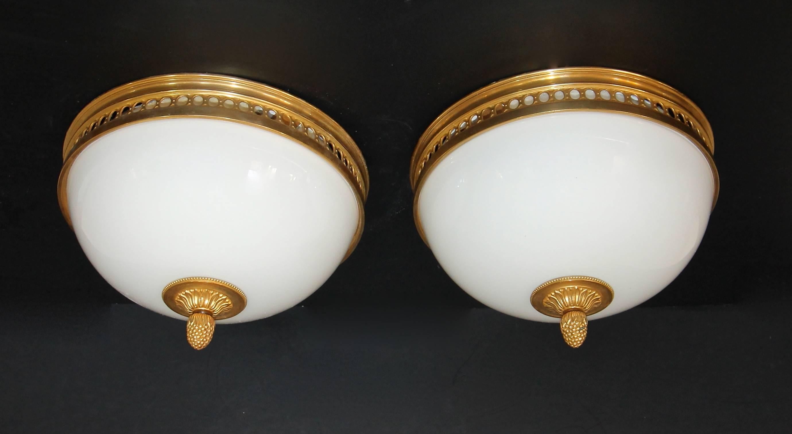 Pair of gorgeous French Louis XVI style flush mount ceiling lights with white opaline glass domes and with high quality finely detailed doré bronze ormolu mounts and acorn finials. Newly wired for US, each fixture uses two - candelabra 