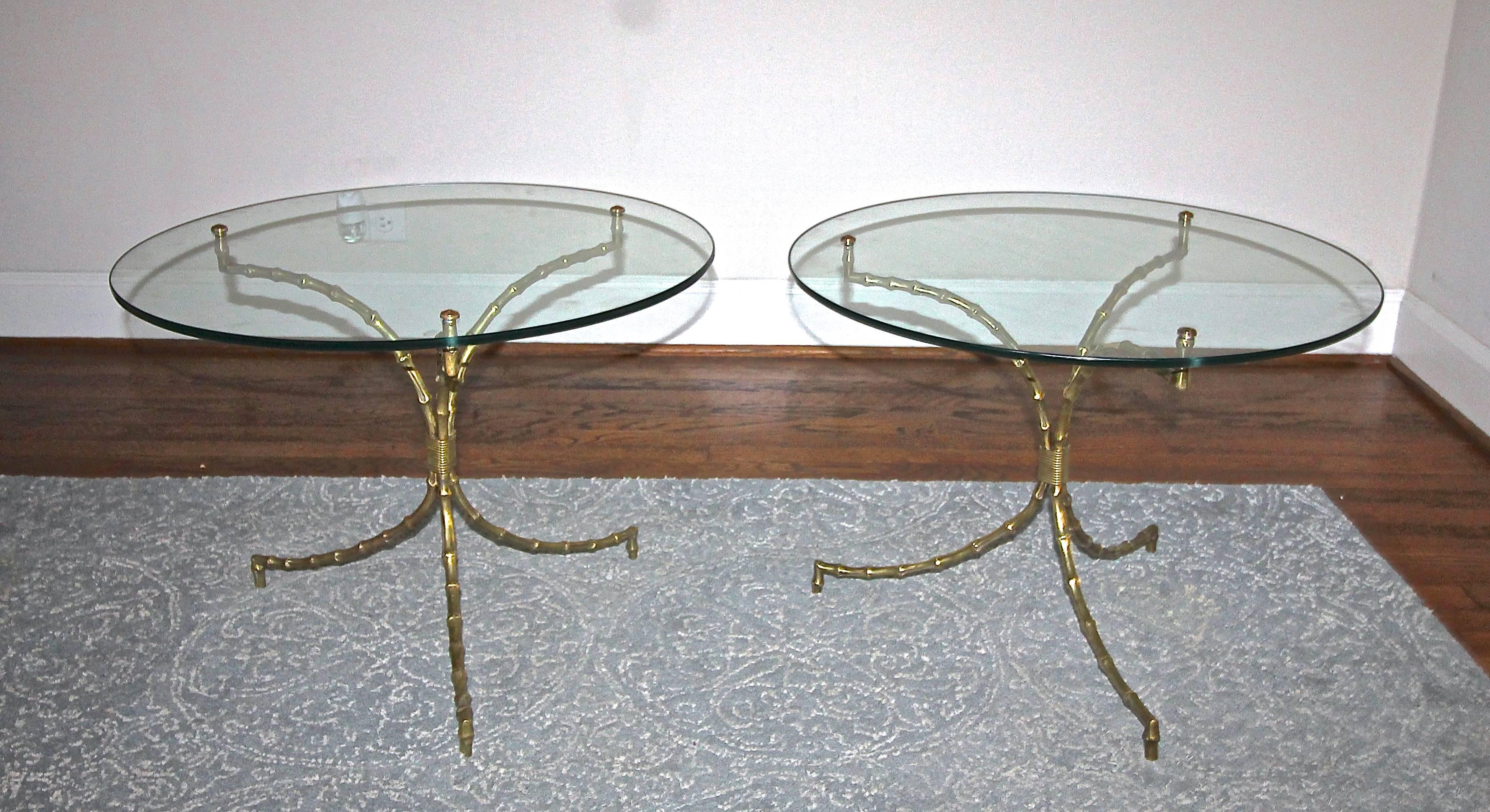 Pair of French Bagues style bronze faux bamboo tripod cocktail or side tables with attached round clear glass tops. The bronze bamboo is nicely detailed with an overall warm aged patina; glass is attached to frame with bronze cap attachments. The