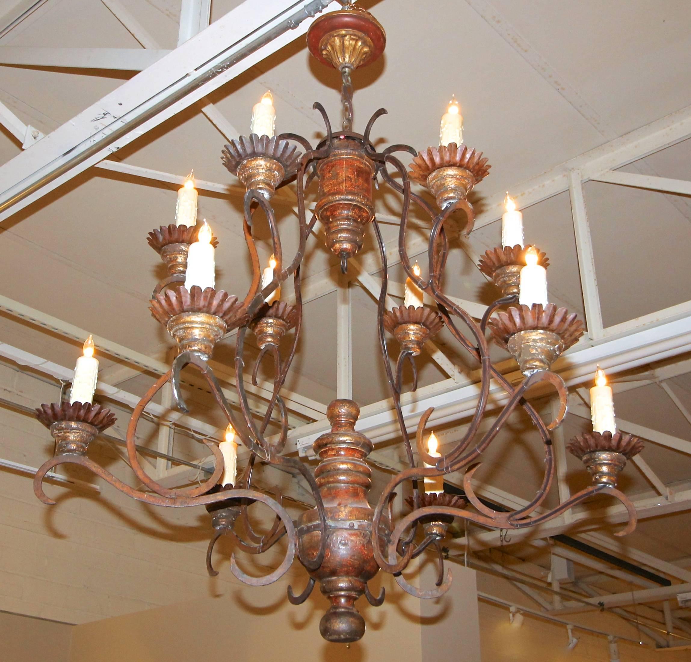 Large Italian style twelve-light cage form chandelier with wood turned elements in aged gilt and painted finish. Aged iron arms and drip pans. Wired for US. 

Overall height including chain and ceiling cap 50