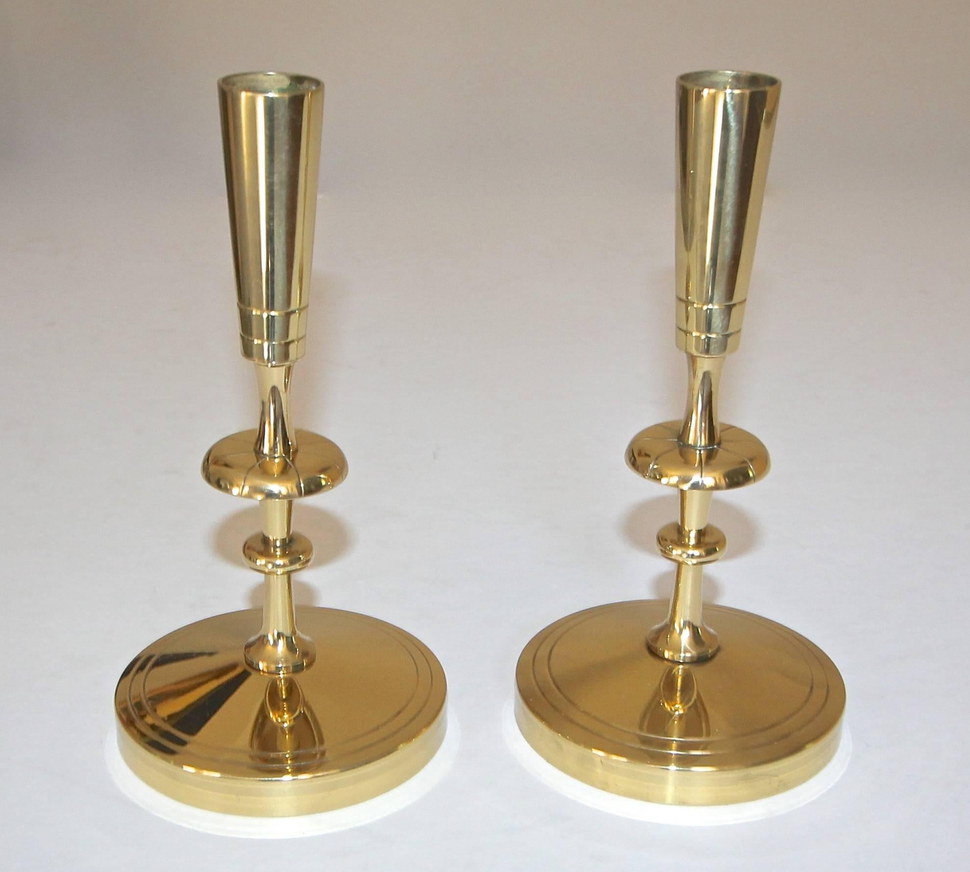 Pair of polished brass candleholders or candlesticks designed by Tommi Parzinger for Vincent Lippe / Dorlyn Silversmiths, New York. Each element of the Dorlyn accessories was handcrafted from sheet brass in New York. This pair has been more recently