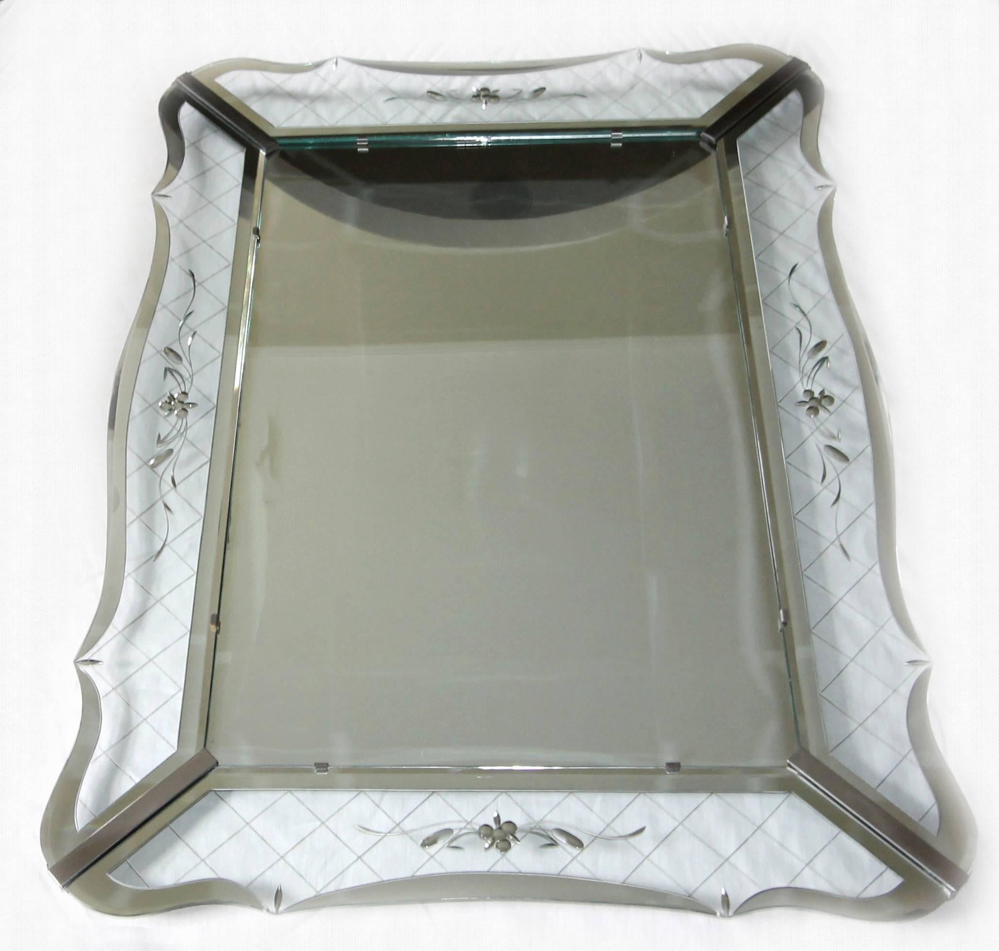 Magnificent large-scale deco style wavy edge wall mirror. The expertly crafted mirror has clear glass panels with a wheel cut and mirrored cross-hatch pattern and mirrored edges. A delicate floral and ribbon motif are central to each panel and are