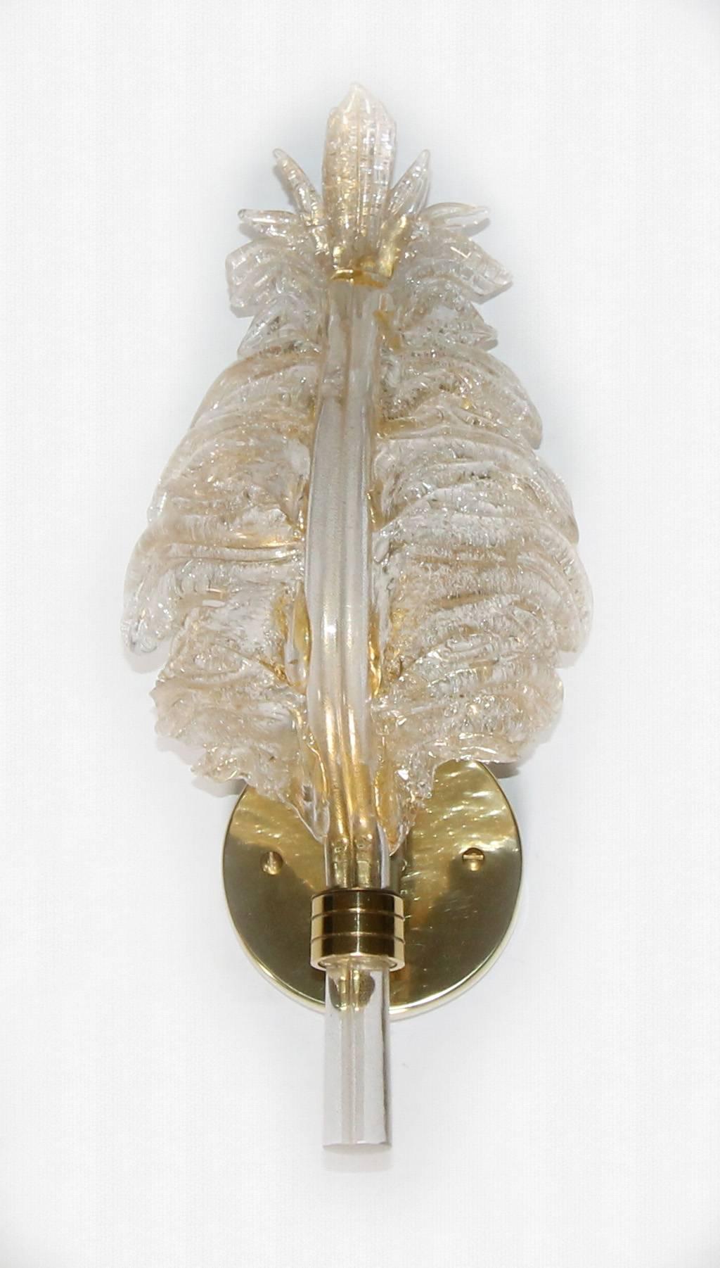 One slender handblown Barovier & Toso glass leaf wall sconce in in clear with heavy gold inclusions. Rugiodoso technique to back of leaf with scattered particles of glass to help diffuse light. Supported on brass backplate, fixture uses one