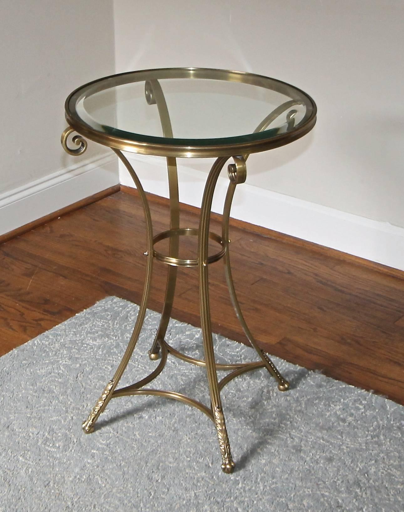 A taller neoclassic style round brass gueridon side or end table with inset bevelled glass table. Well-crafted with nicely detailed paw feet and acanthus leaf details.