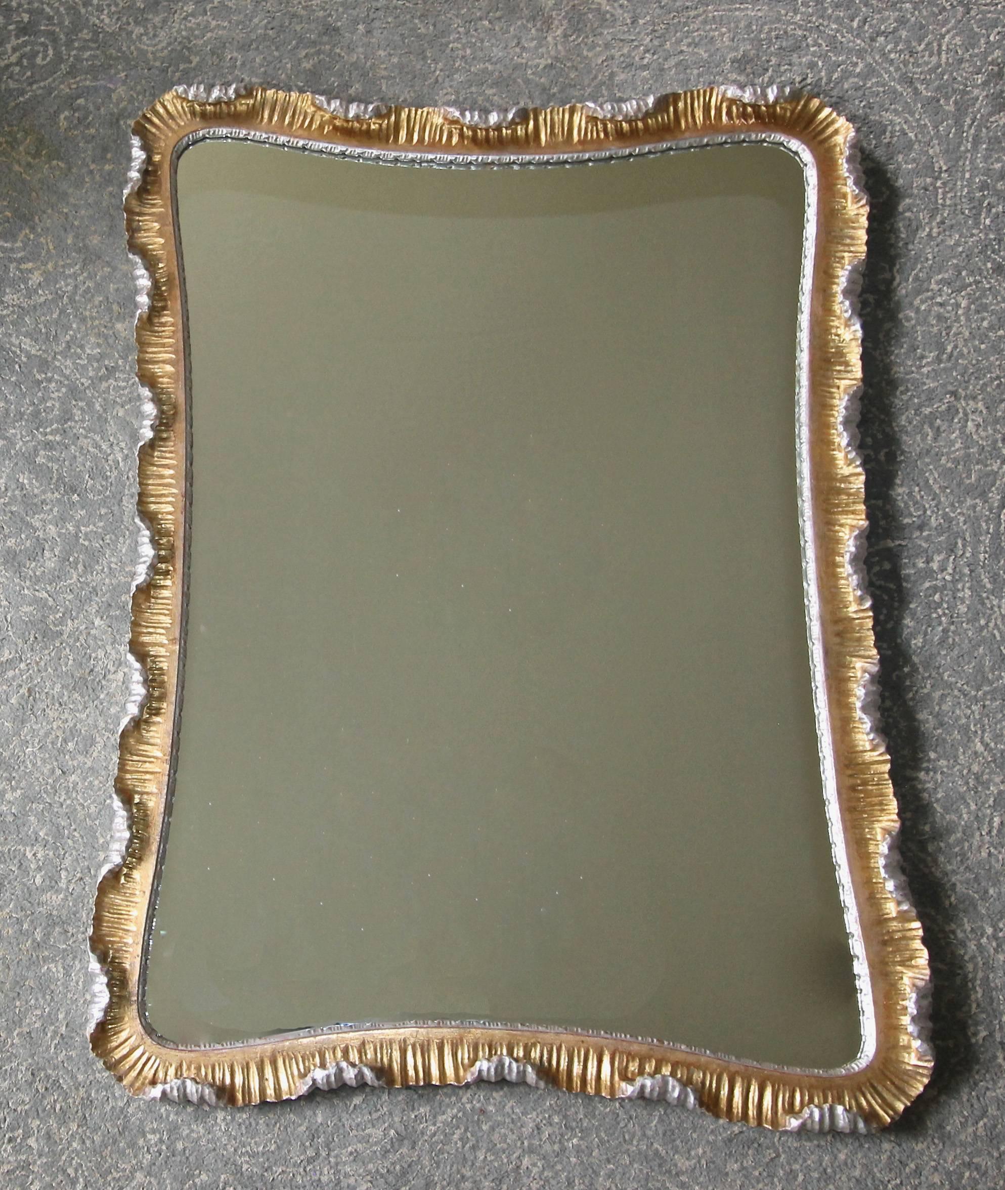 Italian wood carved scalloped edge wall mirror with hand applied gold and silver leafing. A wonderfully crafted Hollywood Regency Mid-Century period wall mirror.
 