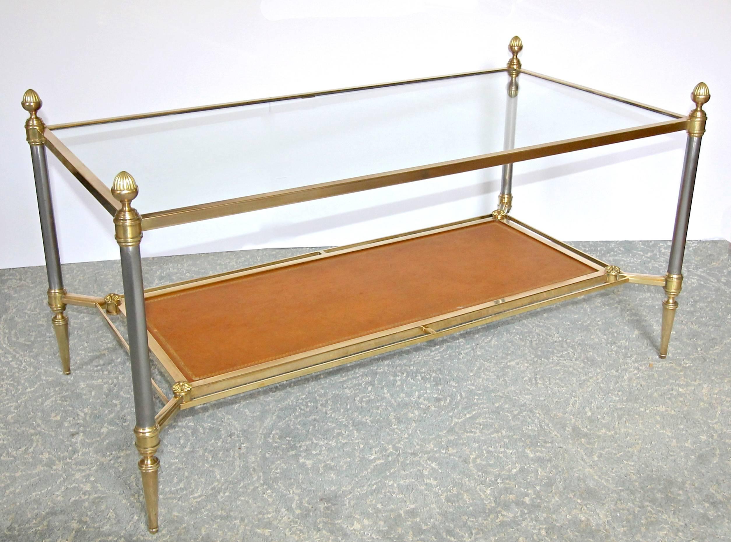 French bronze or brass and polished steel two-tier coffee or cocktail table. Bottom inset shelf has a tan colored tooled leather top with gold Greek key border. Top is original inset glass set into the top from the reverse side. Expertly crafted