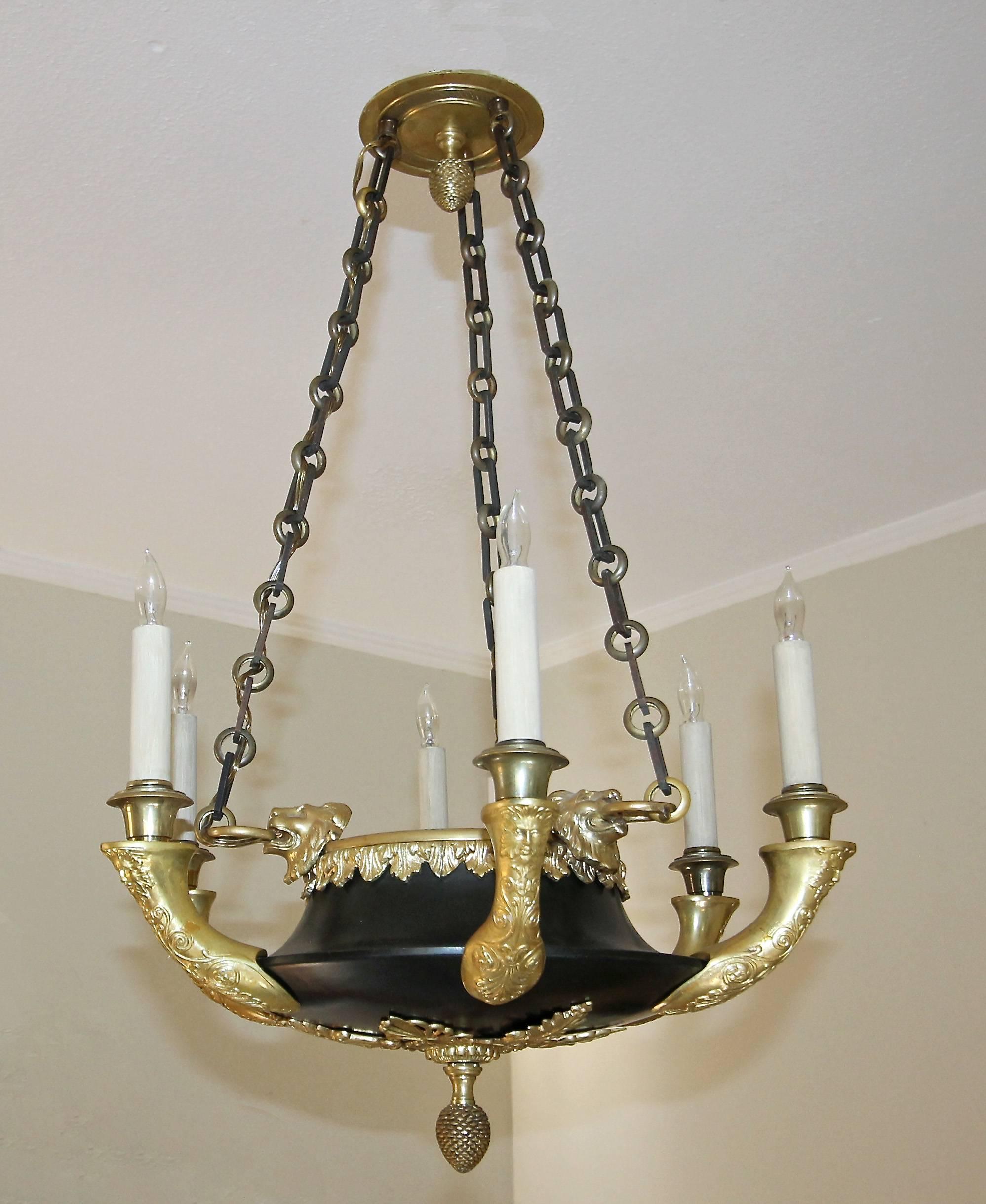 Expertly crafted French late 19th century six-light chandelier in the Empire style decorated with rich detailed neoclassical ornamentation with lion heads, figural satyres mask, palm leaves and pine cone finials. Gilt bronze and tole. Extremely