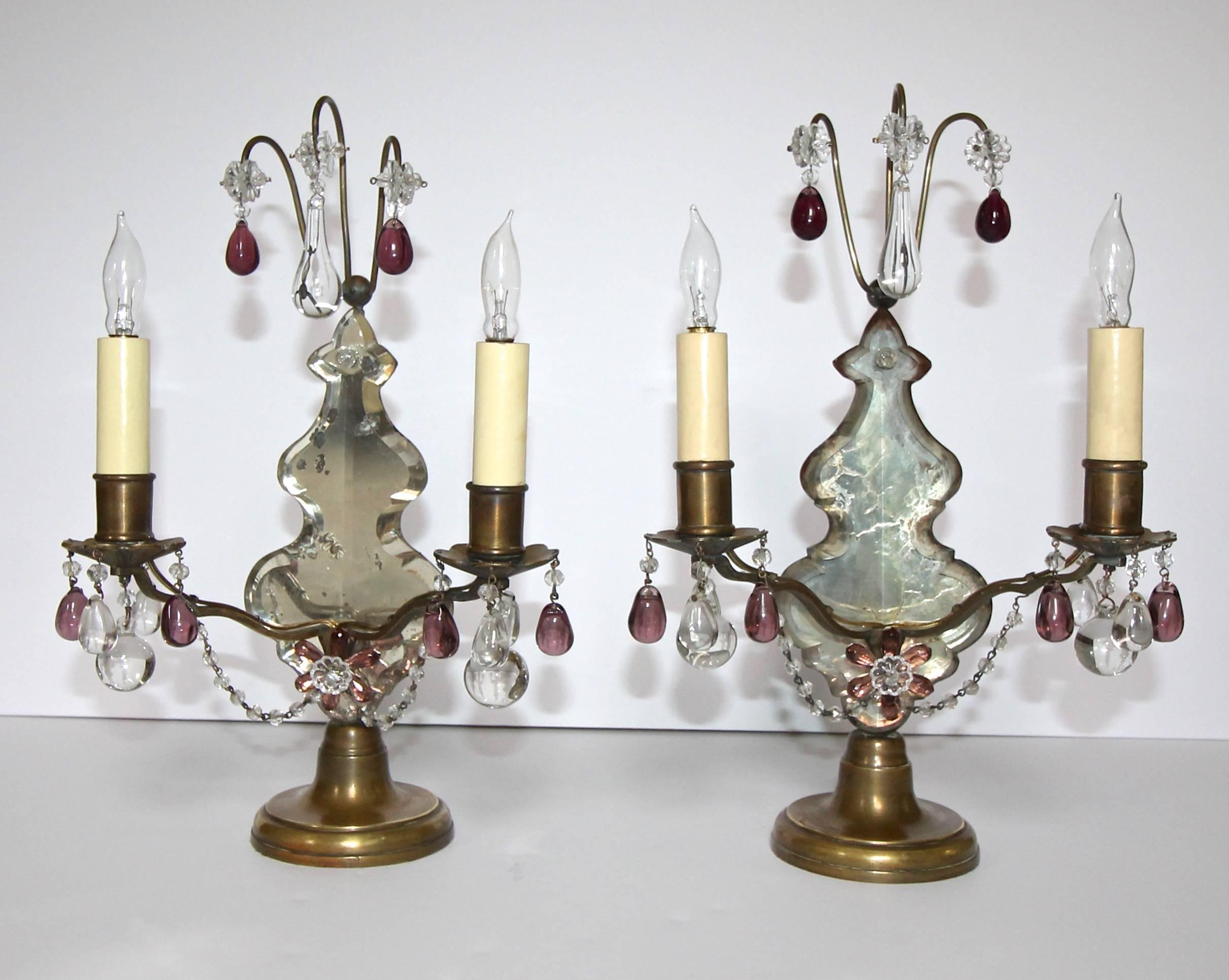 Lovely pair of 1920s French two-light bronze girandoles or mantel lamps with a large mirrored crystal pendalogues. Dressed in clear and amethyst colored glass crystals. Bronze or brass has acquired a warm and deep patina. Well scaled for a mantel in