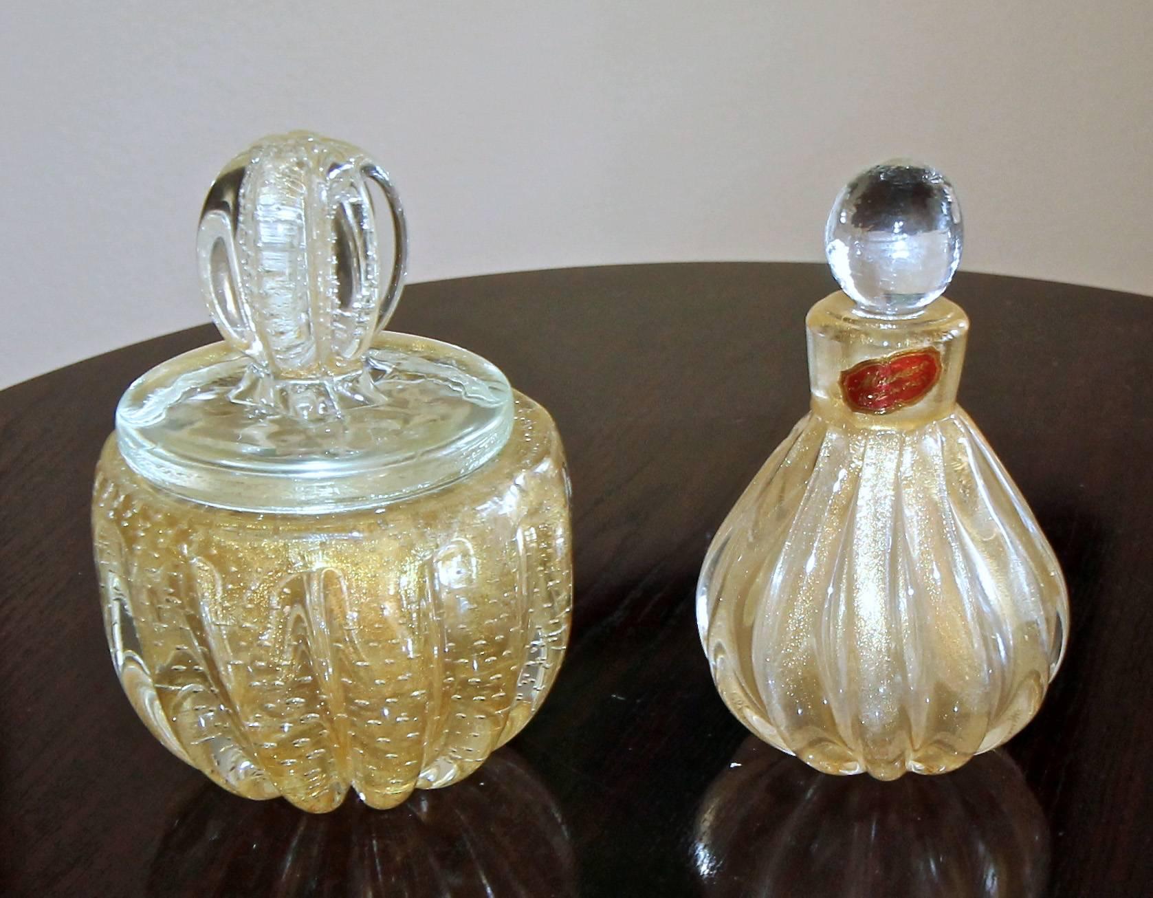 Murano glass perfume bottle and lidded powder jar, each with gold inclusions and controlled bubbles.
Measures: size perfume bottle 5.5" tall x 3.5" wide, powder jar 6" tall x 4" wide.