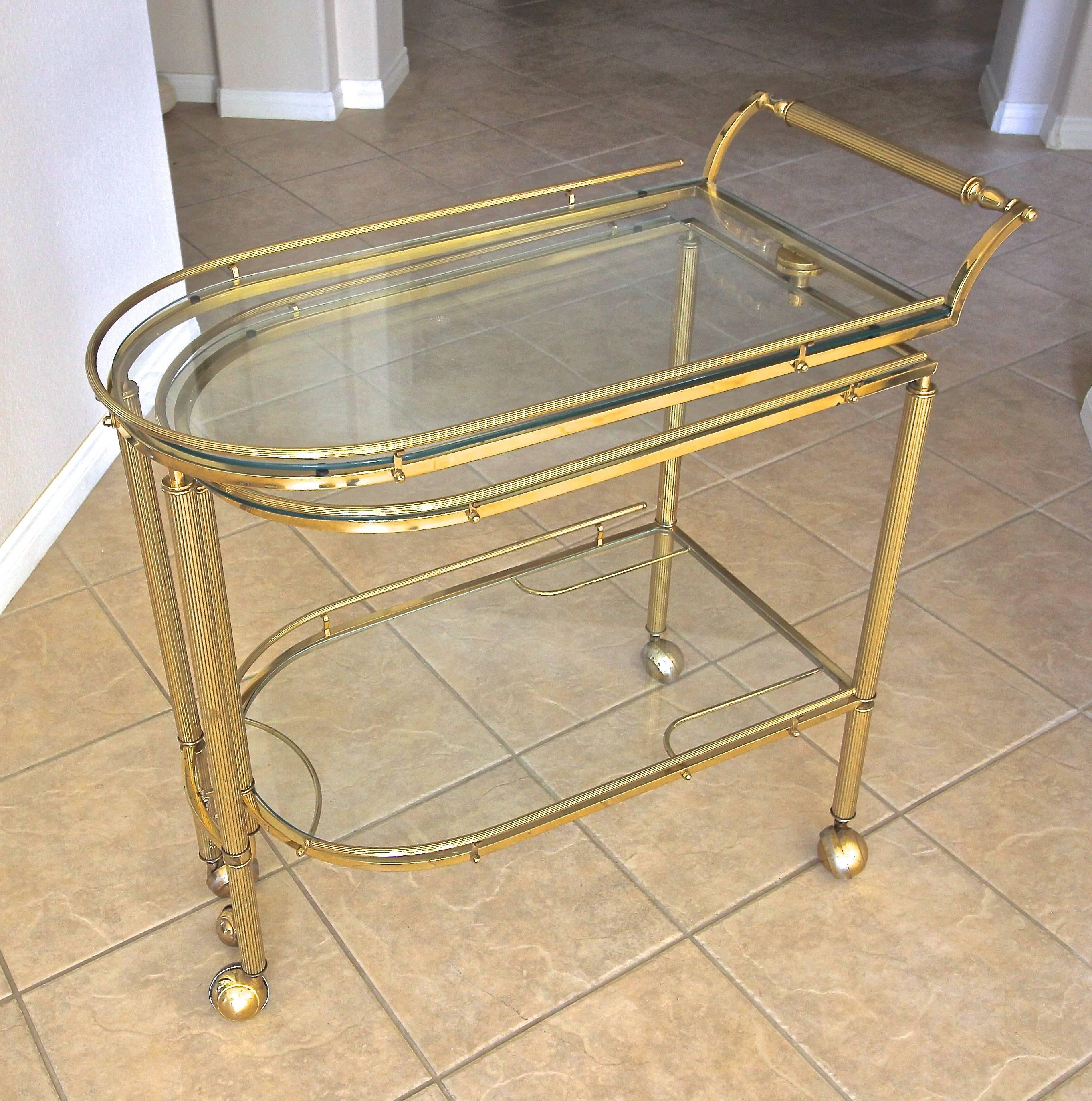 Hard to find vintage Italian three-tier brass bar or tea cart with reeded legs and glass inset tops. The bar cart swivels to open at various positions revealing three surfaces for optimum usage. Well crafted quality piece with rich brass patina. Bar