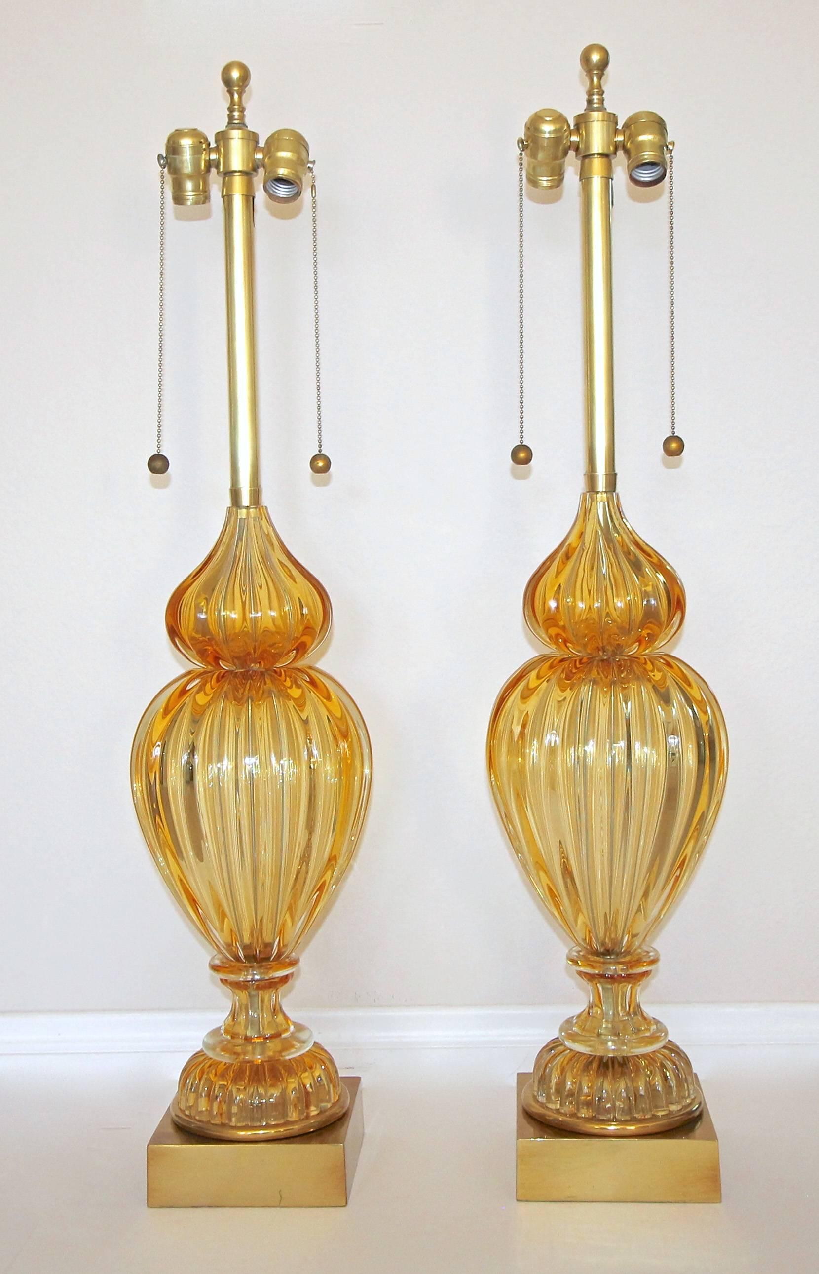 Pair of large Seguso Italian Murano handblown amber ribbed glass table lamps by Marbro. Glass has a rich golden amber color, each resting on original gilt metal bases. Original solid brass double cluster sockets and fittings, newly wired. Retains