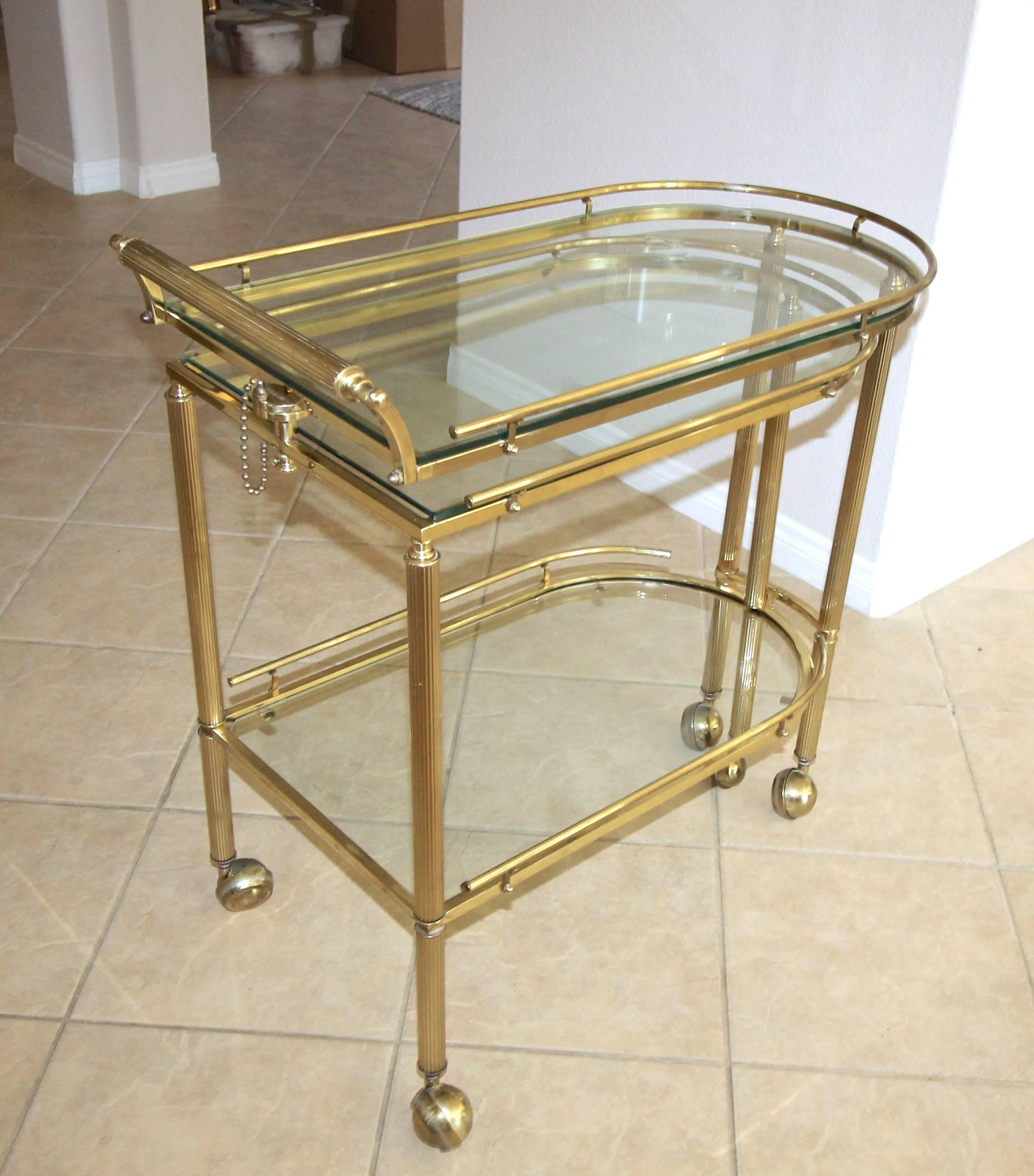 Italian three-tier brass bar or tea cart with reeded legs and glass inset tops. The bar cart swivels to open at various positions revealing three surfaces for optimum usage. Well crafted quality piece. Bar cart fully extended size 53.75