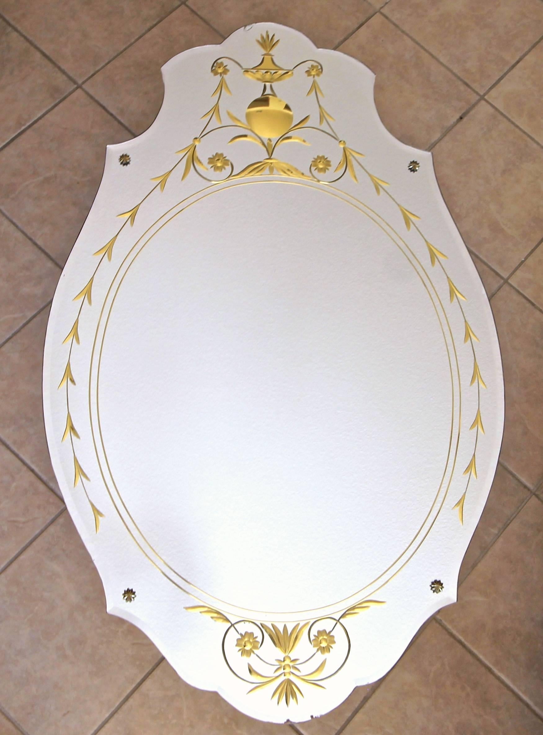 Absolutely beautiful 1930s Art Deco wall mirror with scalloped bevelled edges and brass rosettes. Reverse side is finely etched and gold filled with urn, flower and leaf motif.