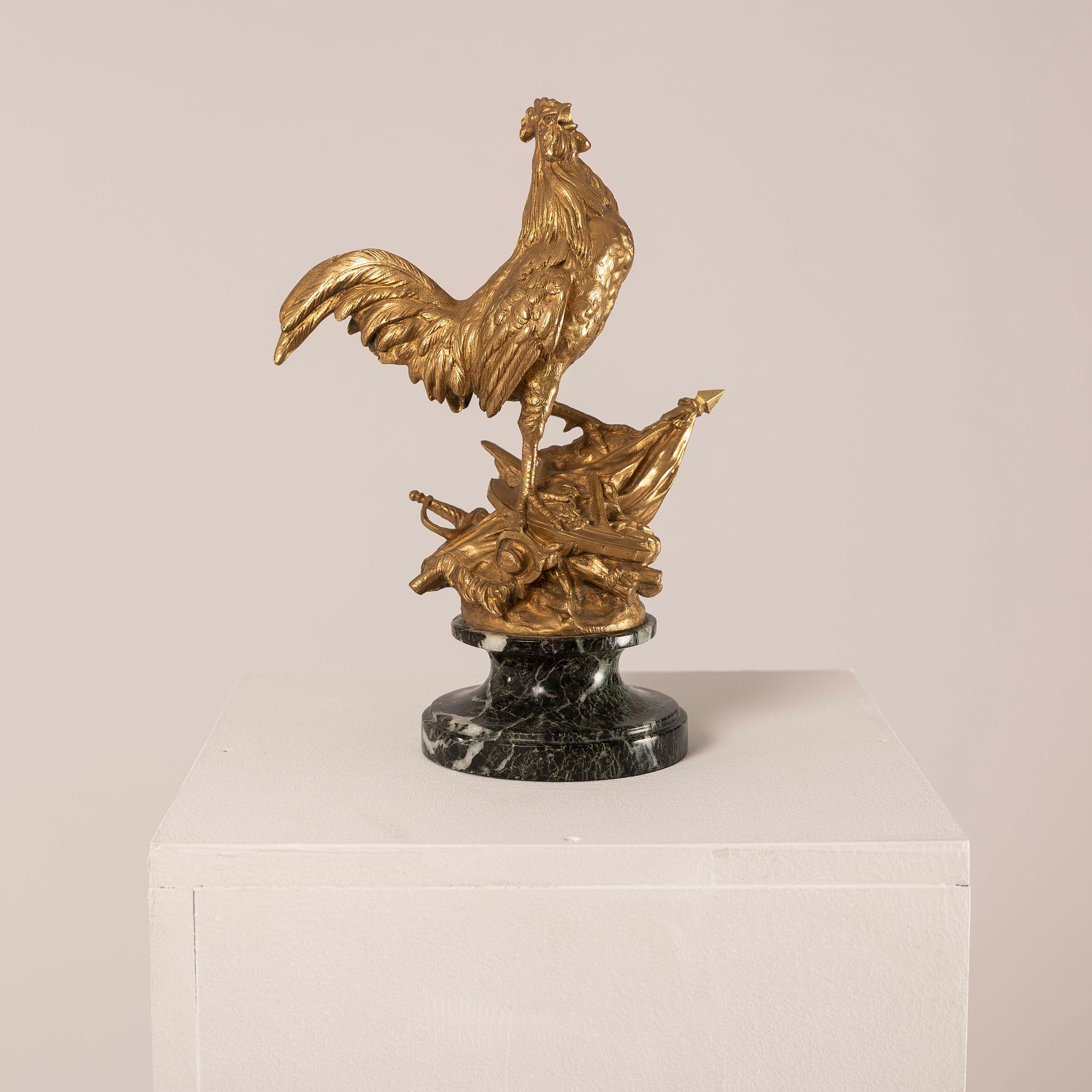 Cette étonnante sculpture en bronze doré, d'après Arthur Comte DU PASSAGE (1838-1909), capture l'image puissante d'un coq fier, symbole national durable de la France, surmontant des éléments militaires et tenant un drapeau. Plus qu'un objet