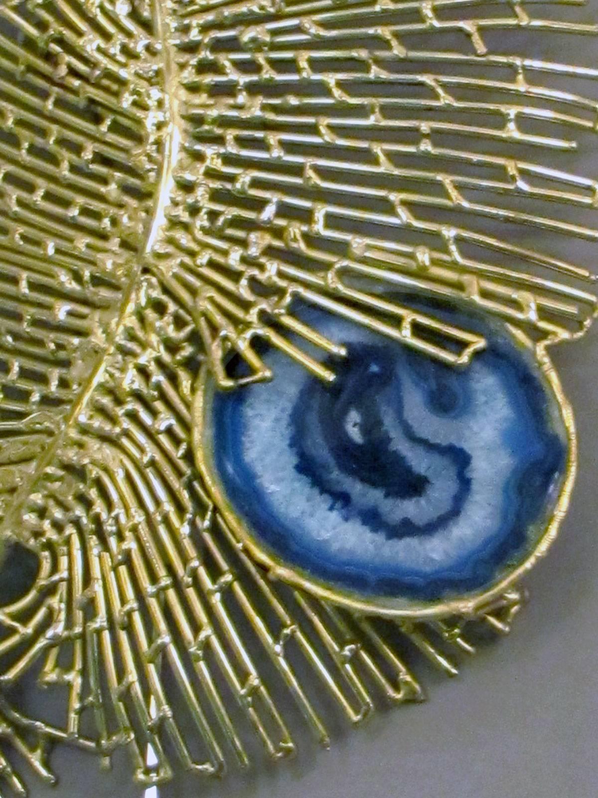 Skulpturale Wandleuchte aus bearbeitetem Messing mit vier Scheiben aus blauem Achat.
Eine Glühbirne ist mittig auf der Rückseite der Applikation versteckt. Unterschrieben.