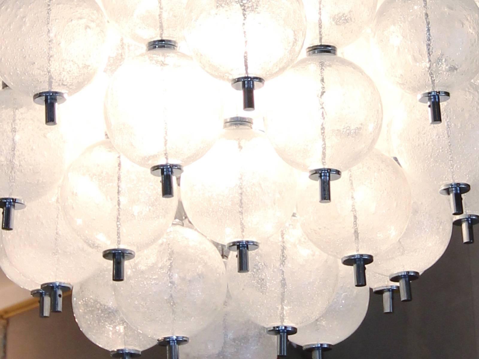 Rare ceiling light by  Zero Quattro in Milano, Italy, 1980.
Many spheres in Murano (probably made by Mazzega) bubble glass are suspended using chains to a ceiling in chrome metal. Three-light bulbs are hidden in the middle of the chandelier.
